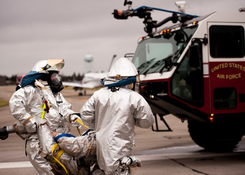 Youngstown Air Reserve Station firefighters carry a simulated victim from a C-130 to a triage area during a Major Accident Readiness Exercise here, April 23, 2014. In the exercise scenario, a C-130 aircraft’s landing gear collapsed while landing on the assault strip. Debris from the aircraft hit a private aircraft taxiing nearby. Base emergency response personnel tested their response capability while Wing Inspection Team (WIT) members observed. U.S. Air Force photo/Eric M. White.