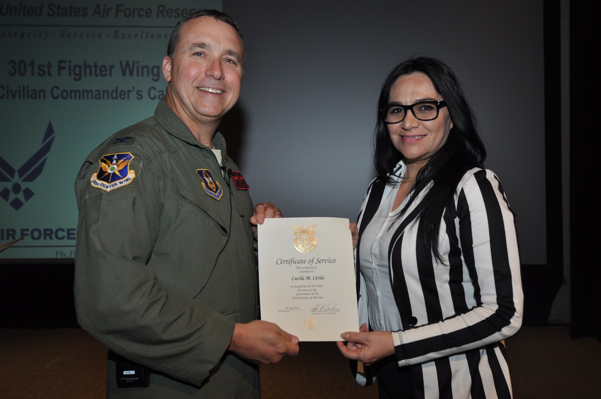 Ms. Lucila Cerda, 301st Fighter Wing command staff, receives her 10-year pin and certificate for civilian service from Col. John Breazeale, 301st FW commander, at a ceremony April 7, 2014.