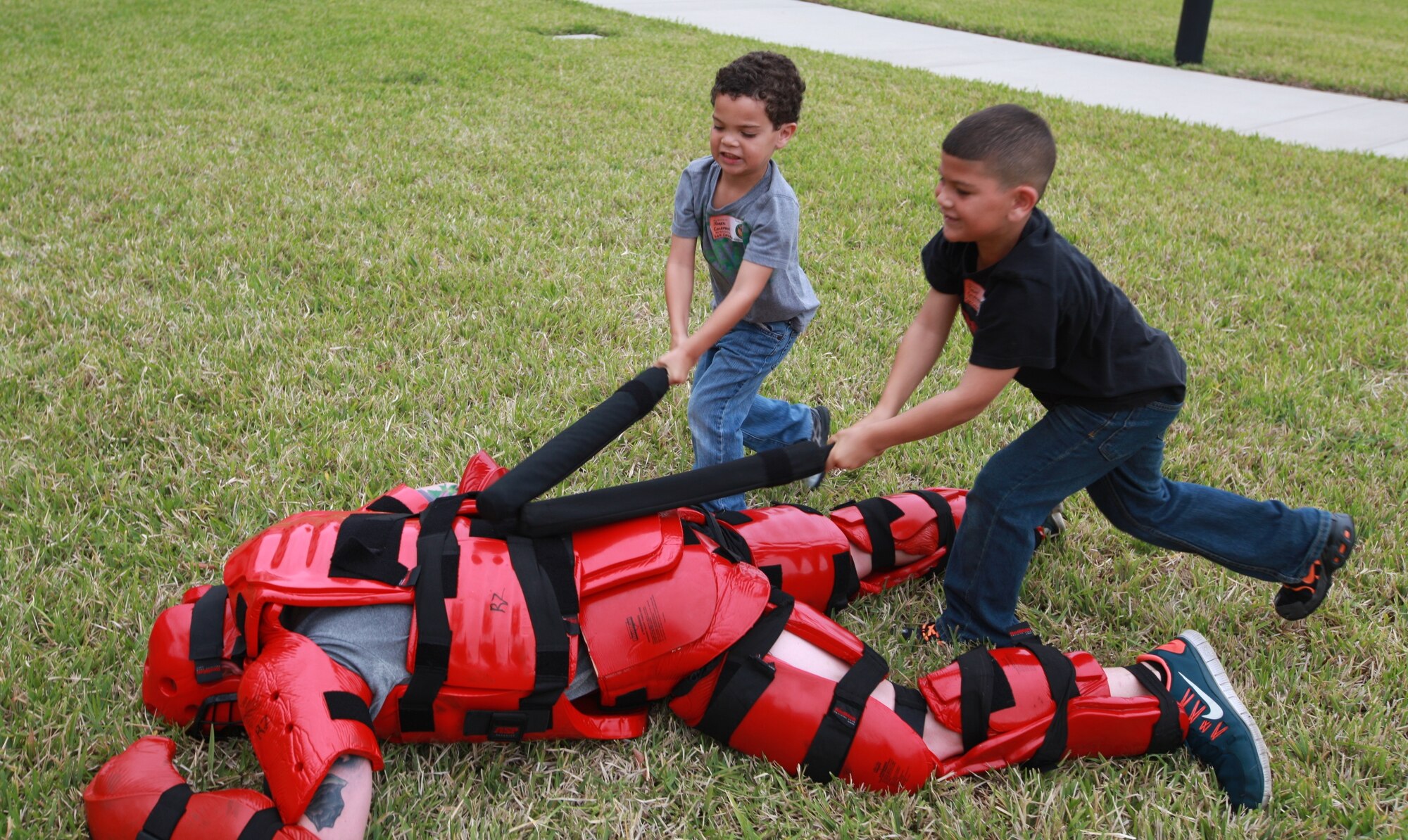 Jared (left) and Trent, sons of Sgt. Fredrick J. Coleman, U.S. Central Command public affairs, team up to defeat the “Big Red Guy” as their name for him, during the baton training demonstration during USCENTCOM’s  Family Open House at MacDill Air Force Base, Fla., April 18.  (U.S. Marine Corps photo by Sgt. Fredrick J. Coleman/Released)