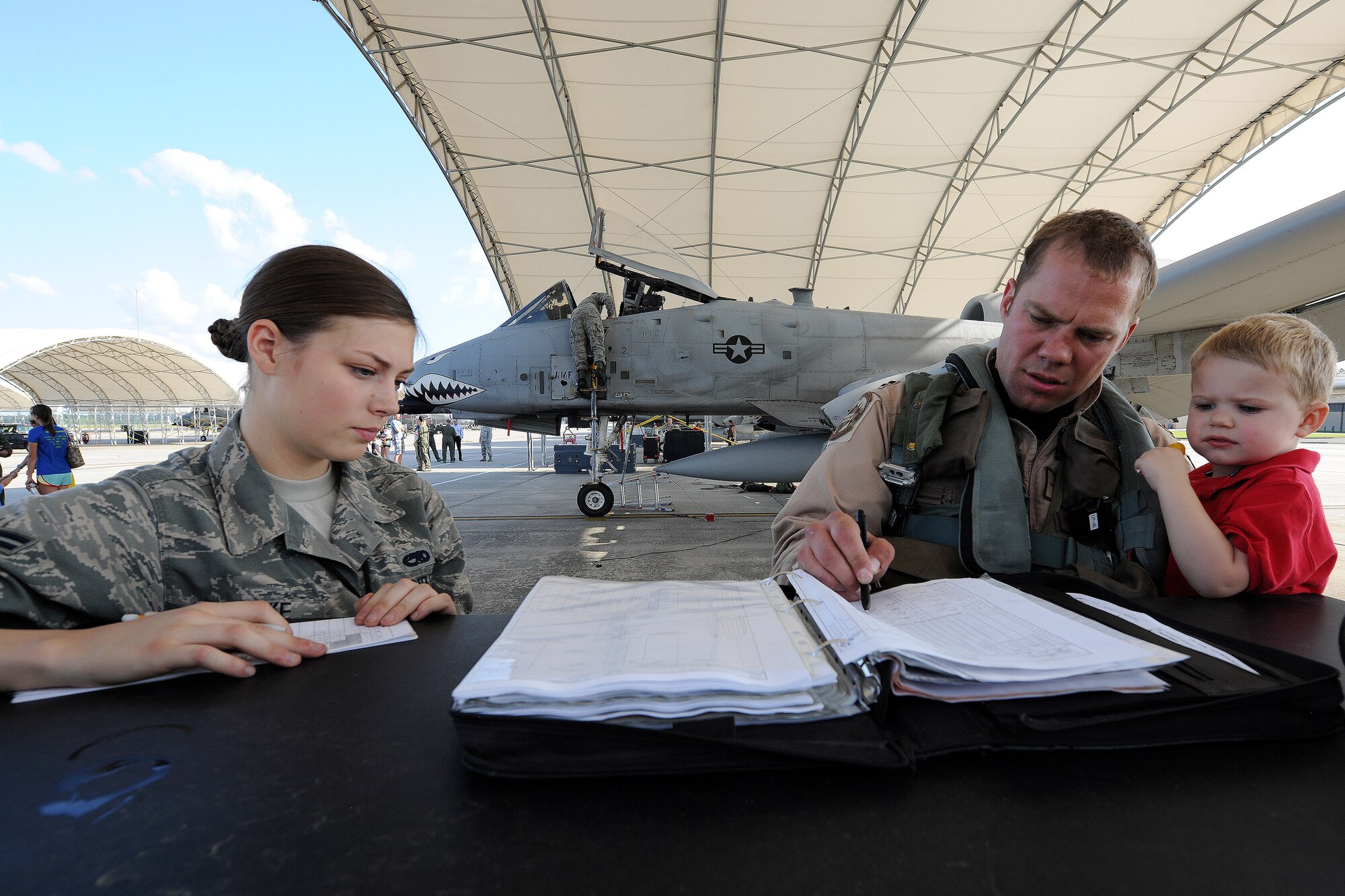 U.S. Air Force Capt. Leif Nordhagen, an A-10C Thunderbolt II pilot assigned to the 75th Fighter Squadron, holds his son Lars while completing post-flight forms with Airman 1st Class Robin Burke, an A-10 crew chief with the 23d Aircraft Maintenance Squadron.  Nordhagen returned to Moody following a six-month deployment to Afghanistan. 
(U.S. Air Force photo by Master Sgt. Sonny Cohrs/Released)
