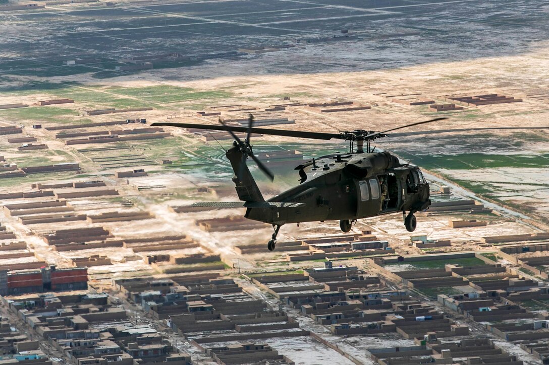 An MH-60 Black Hawk helicopter flies over a village for a leaflet drop in Balkh province, Afghanistan, April 13, 2014. 