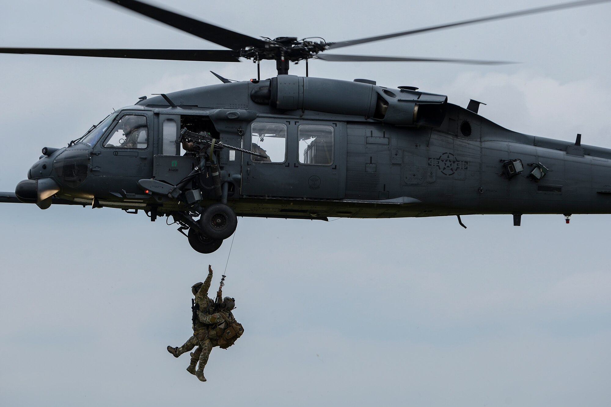 Chief Master Sgt. Chad Clark and Maj. Patrick Gruber hang from an HH-60G Pave Hawk after the successful recovery of a mock crash victim during a combat search and rescue exercise April 17, 2014, at Royal Air Force Lakenheath, England. Clark is the superintendent of the 56th Rescue Squadron and Gruber is the 56th RQS director of operations. The honorary commanders witnessed the training firsthand during a tour. (U.S. Air Force photo/Airman 1st Class Trevor T. McBride)
