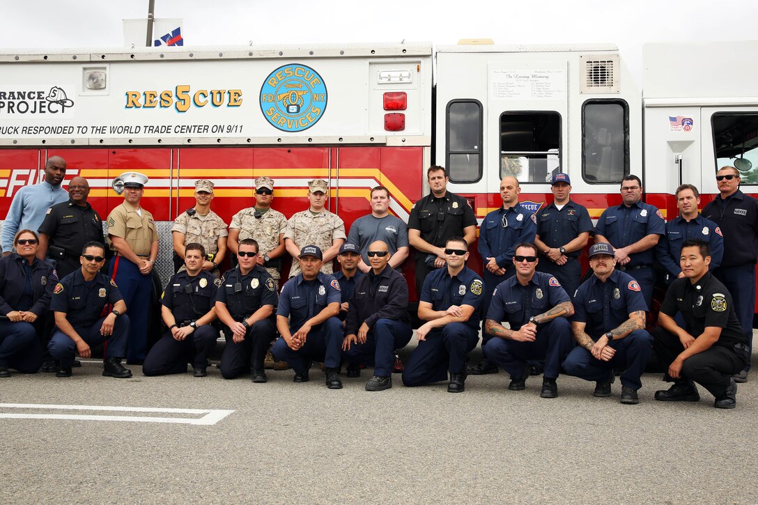 Members of the Remembrance Rescue Project, base firefighters from station three and five, and members of the Camp Pendleton Provost Marshalls Office gather in front of Rescue 5 during its visit to Camp Pendleton April 25. The Remembrance Rescue Project was created by firefighters to restore Rescue 4 and Rescue 5 as an educational effort for society, especially for those too young to remember the events of September 11. Rescue 4 and 5 are rescue engines used by New York emergency personnel during the events of September 11.