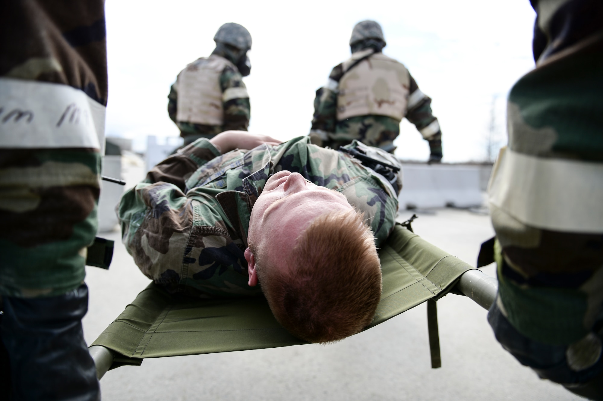 Eielson Icemen carry a simulated injured Airman to a casualty collection point during Ability to Survive and Operate training April 22, 2014, Eielson Air Force Base, Alaska. The exercise helped build teamwork for improving response times and work efficiency in a controlled training environment simulating chemical and explosive attacks. (U.S. Air Force photo by Senior Airman Peter Reft/Released)