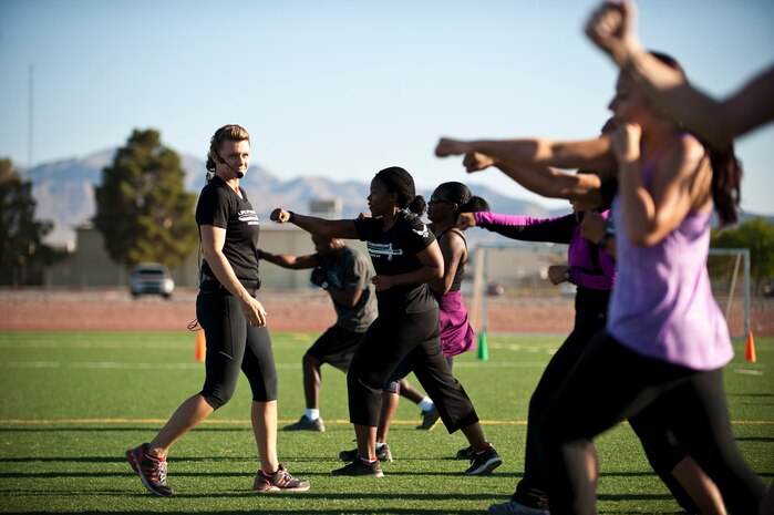 Missy Cornish, wife of Col. Barry Cornish, 99th Air Base Wing commander, leads a group during a Warrior Trained Fitness workout on the field behind the Warrior Fitness Center April 24, 2014, at Nellis Air Force Base, Nev. Cornish has led multiple Warrior Trained Fitness workouts involving both military and civilian participants. (U.S. Air Force photo by Airman 1st Class Thomas Spangler)