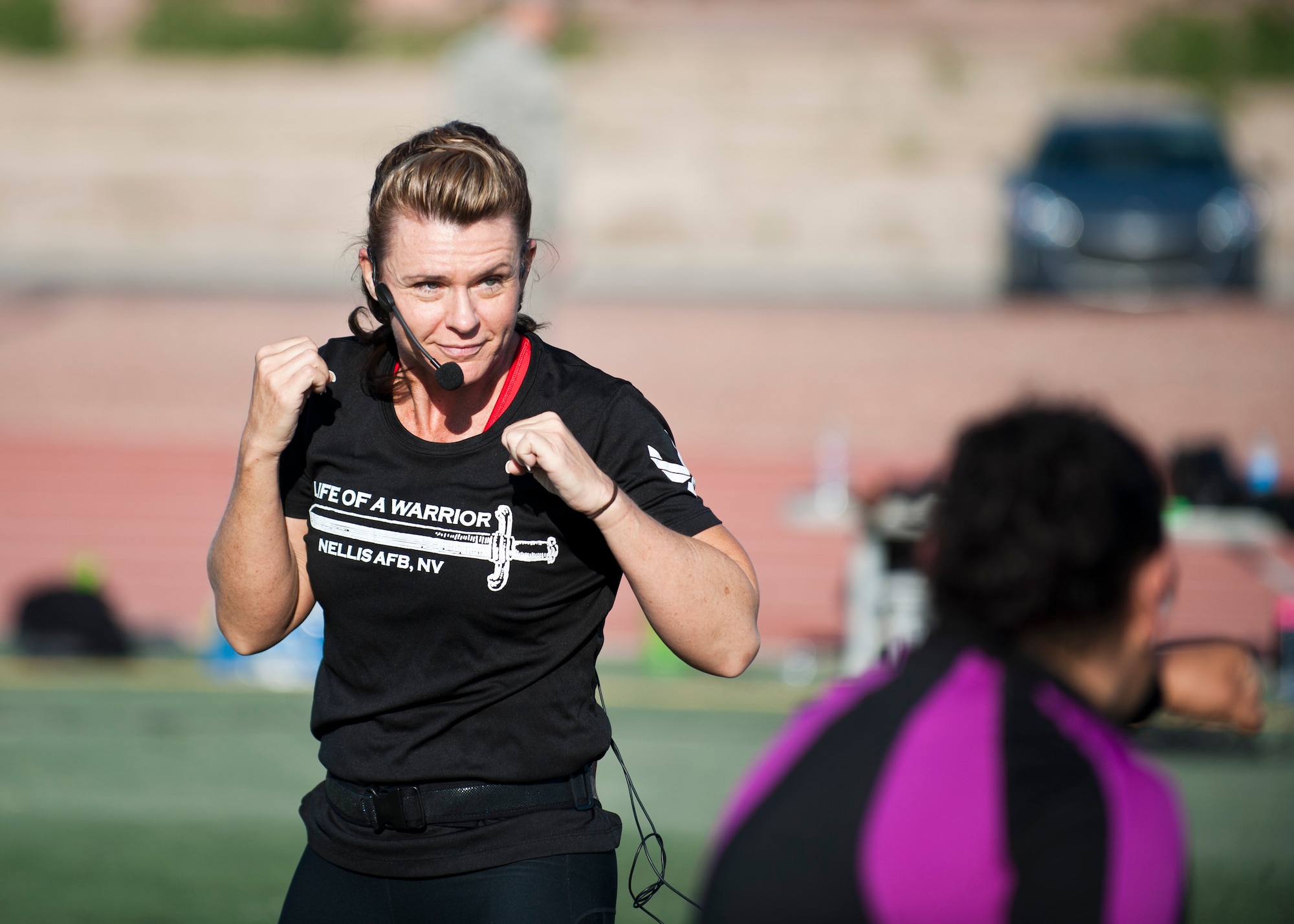 Missy Cornish, wife of Col. Barry Cornish, 99th Air Base Wing commander, leads a group during a Warrior Trained Fitness workout on the field behind the Warrior Fitness Center April 24, 2014, at Nellis Air Force Base, Nev. WTF is a high-intensity workout designed as part of the “Life of a Warrior” concept encouraging individuals to live a healthier lifestyle. (U.S. Air Force photo by Airman 1st Class Thomas Spangler)