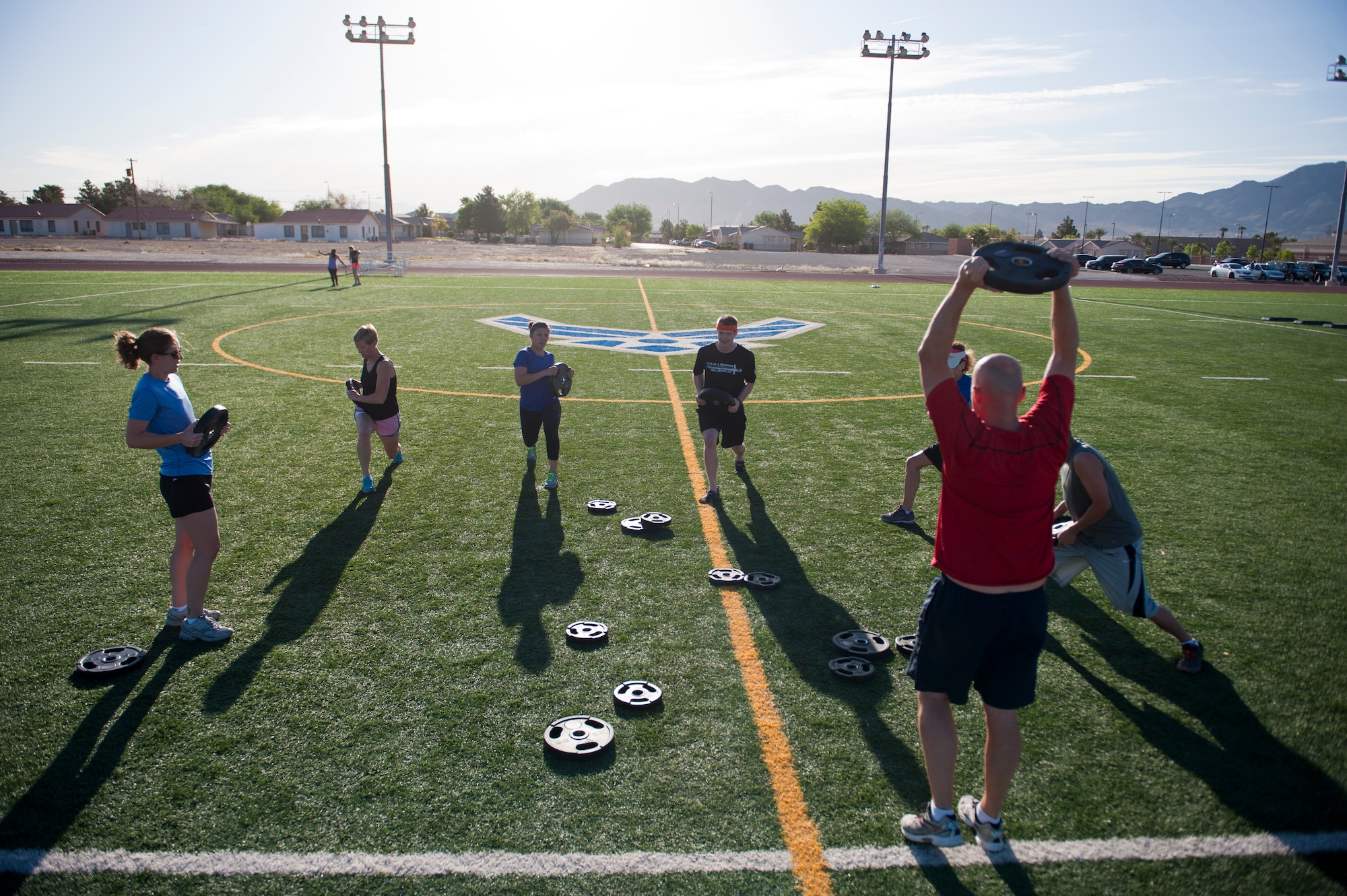 Participants in the Warrior Trained Fitness exercise do forward lunges with weights at the Warrior Fitness Center April 24, 2014, at Nellis Air Force Base, Nev. The WTF workout consists of multiple stations each with a different exercise meant to strengthen different parts of the body. (U.S. Air Force photo by Airman 1st Class Thomas Spangler)