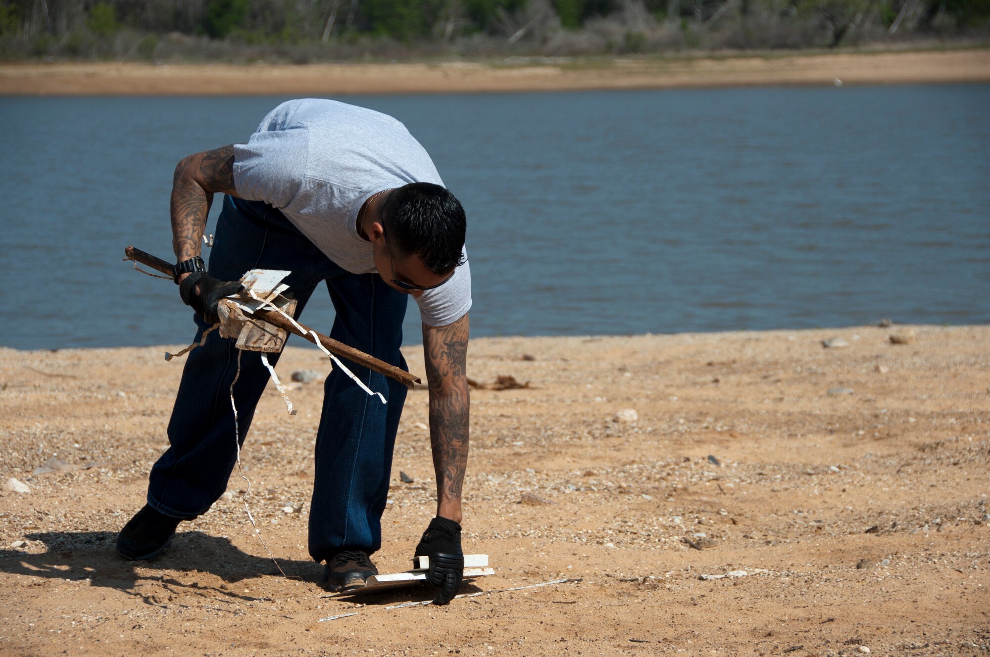 Army Staff Sgt. Miguel Acuna, 366th Training Squadron instructor, picks up litter and debris along the shoreline of Lake Texoma, April 22, 2014. Acuna was one of 11 volunteers from Sheppard Air Force Base, Texas, who participated in an Earth Day clean-up event geared toward ridding the beach of hazardous objects and litter exposed by the low water levels. (U.S. Air Force photo/Airman 1st Class Robert L. McIlrath) 