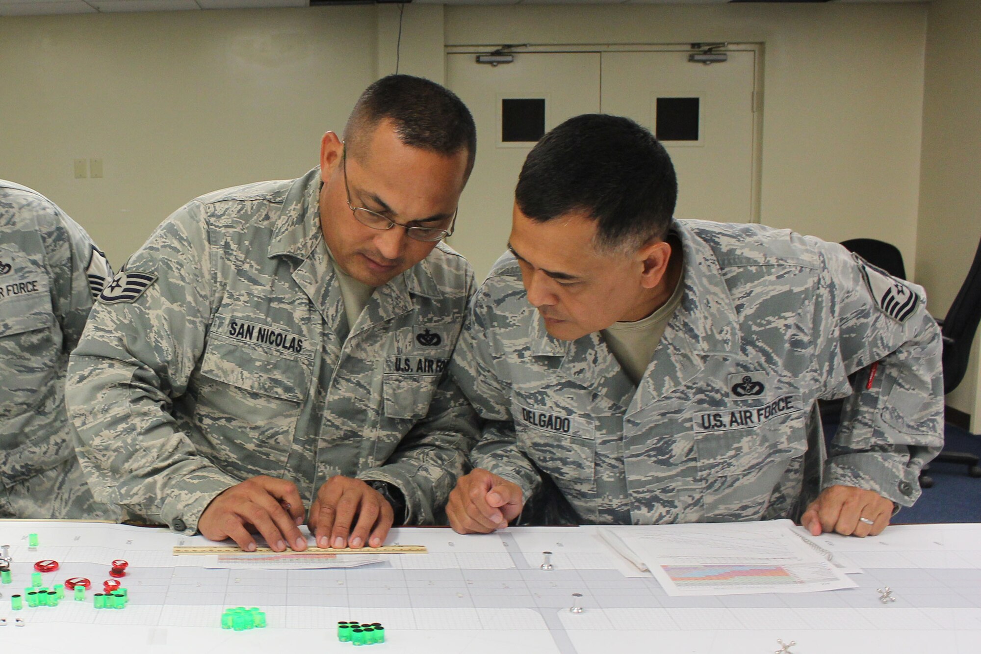 ANDERSEN AIR FORCE BASE, Guam. -- From left, Staff Sgt. Joseph San Nicolas and Master Sgt. John Delgado, 254th RED HORSE Squadron, study a repair timetable during an airfield damage repair tabletop exercise here Jan. 16. The exercise, led by members of the Air Force Civil Engineer Center's Det. 1. at Tyndall AFB, Fla., simulates the process needed to recover an airfield after an attack and return it to service as quickly as possible. AFCEC and Pacific Air Forces are working together to address ADR training needs and develop plans to posture equipment and materials. (U.S. Air Force photo/Scott Smith)