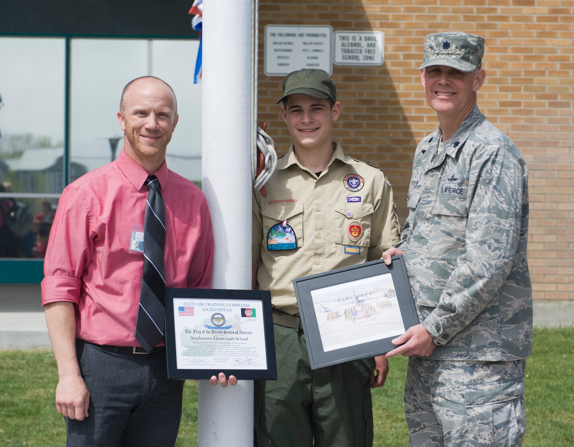 U.S. Air Force Lt. Col. Larry Estes, 366th Mission Support Group deputy commander, Phil McClusky, Mountain Home Air Force Base Primary School principal, and Josh Meyers, senior patrol leader for Boy Scout troop 102, pose in front of the flag pole, April 23, 2014, at Mountain Home Air Force Base, Idaho. Estes presented a flag, which was flown over Iraq, to the Base Primary School to hang on the new flag pole that was installed earlier in April. (U.S. Air Force photo by Airman 1st Class Brittany A. Chase/Released)