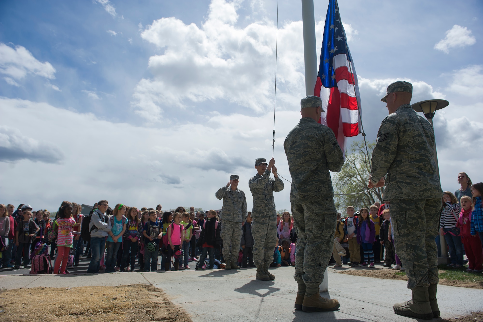 U.S. Air Force Airmen from the Base Honor Guard raise a flag, April 23, 2014, at Mountain Home Air Force Base, Idaho. The Base Primary School held an assembly for the raising of the flag on their new flag pole they received at the beginning of April. (U.S. Air Force photo by Airman 1st Class Brittany A. Chase/Released)