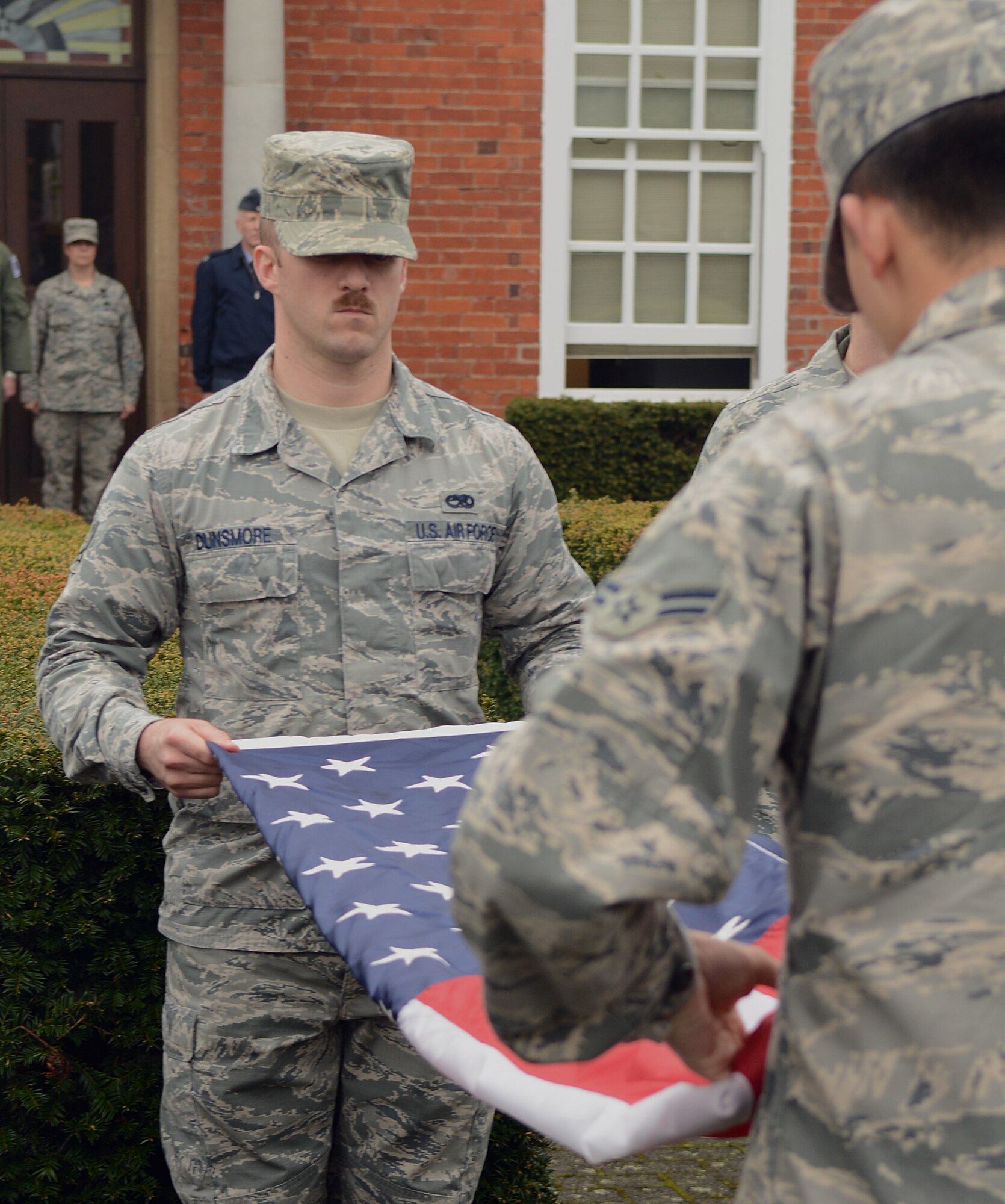 Members of a Team Mildenhall flag detail fold the U.S. flag and Royal Air Force ensign during a retreat ceremony April 25, 2014, on RAF Mildenhall, England. A retreat ceremony, in which the honor guard retires the U.S. flag and RAF ensign, is scheduled to take place the last Friday of every month. (U.S. Air Force photo by Airman 1st Class Jonathan Light/Released)
