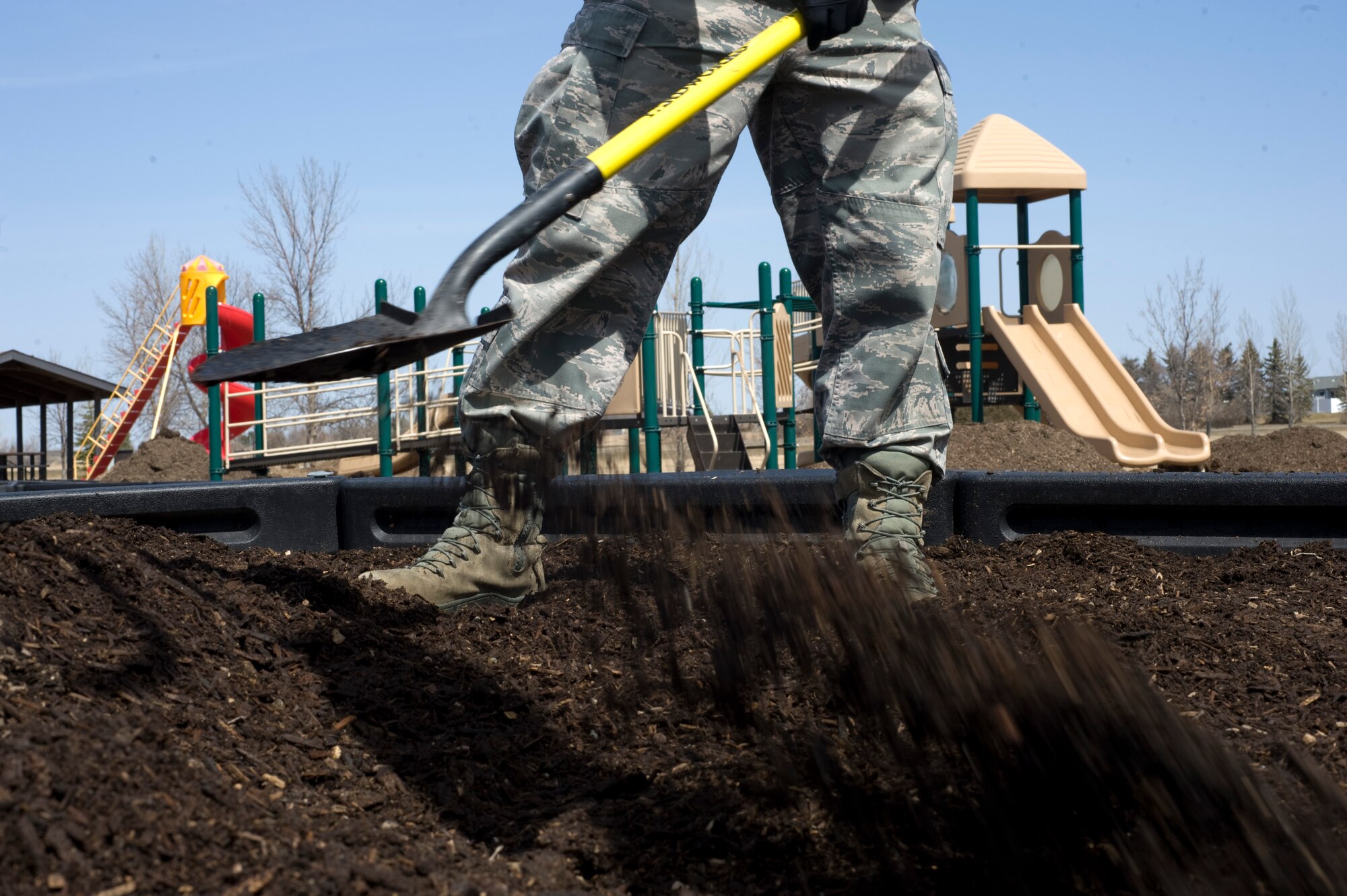 An Airman from the 5th Civil Engineer Squadron spreads mulch at a playground during Earth Day on Minot Air Force Base, N.D., April 21, 2014. Airmen from across the base cleaned up base parks, picked up trash and completed other projects to beautify the base and take care of the environment. (U.S. Air Force photo/Senior Airman Malia Jenkins) 