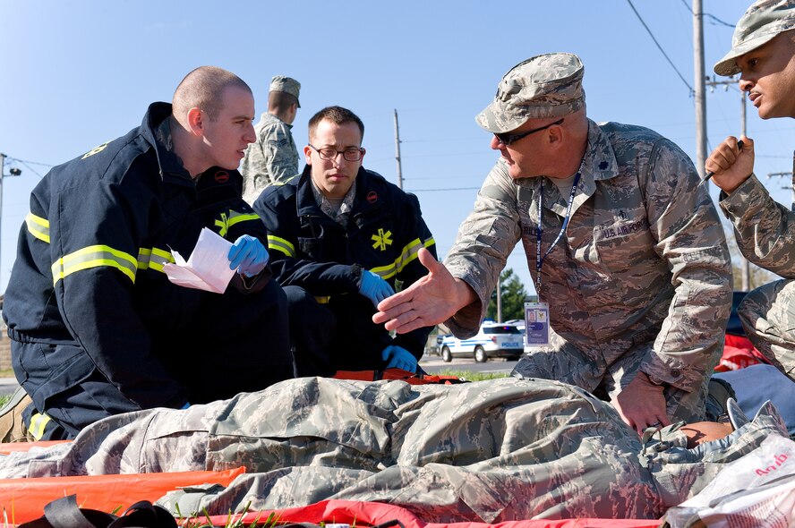 Lt. Col. Douglas Riley, second from right, 436th Aerospace Medicine Squadron officer in charge of public health, talks to Senior Airman Dan Gelman, left, and Senior Airman Adrian Thomas, second from left, both 436th Medical Operations Squadron aerospace medical services technicians April 23, 2014, at Dover Air Force Base, Del. Riley explained triage procedures on simulated fuel spill victim Airman 1st Class Kiara Reed, 436th Aerospace Medical Squadron public health technician while Master Sgt. Jason Walls, right, 436th MDOS family health flight chief, evaluates Gelman and Thomas. (U.S. Air Force photo/Roland Balik)