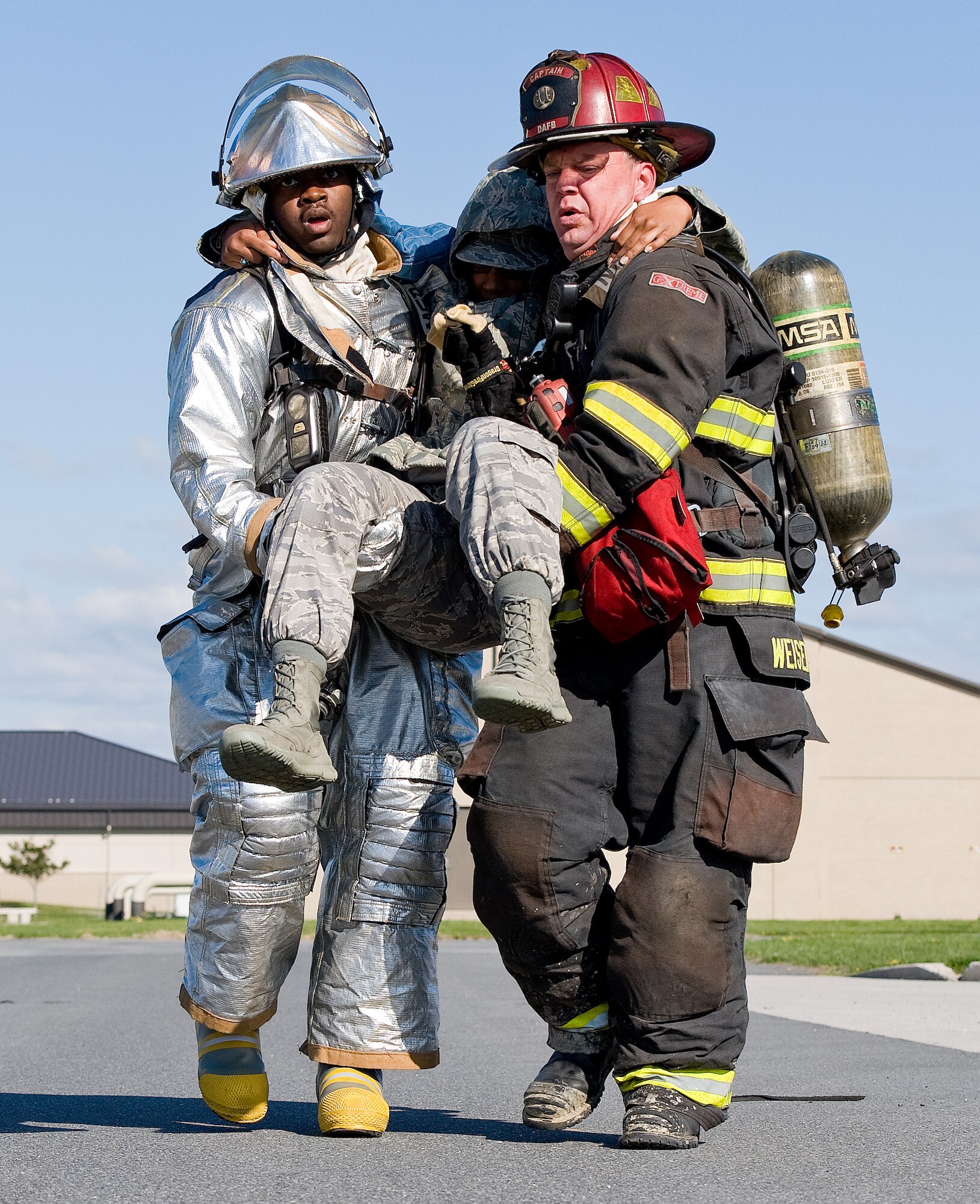 Senior Airman Dequan Griffin, left, a fire protection apprentice with the 459th Civil Engineer Squadron Fire Department, Joint Base Andrews, Md., and Aaron Weisenberger, right, a fire protection crew chief with the 436th Civil Engineer Squadron Fire Department, Dover Air Force Base, Del., use a two-man carry to move simulated fuel spill victim Airman 1st Class Kiara Reed, 436th Aerospace Medical Squadron, Dover AFB, public health technician, to the triage area April 23, 2014, at Dover AFB. Weisenberger and Griffin took turns carrying Reed and used different types of carries on the way to a triage area. (U.S. Air Force photo/Roland Balik)