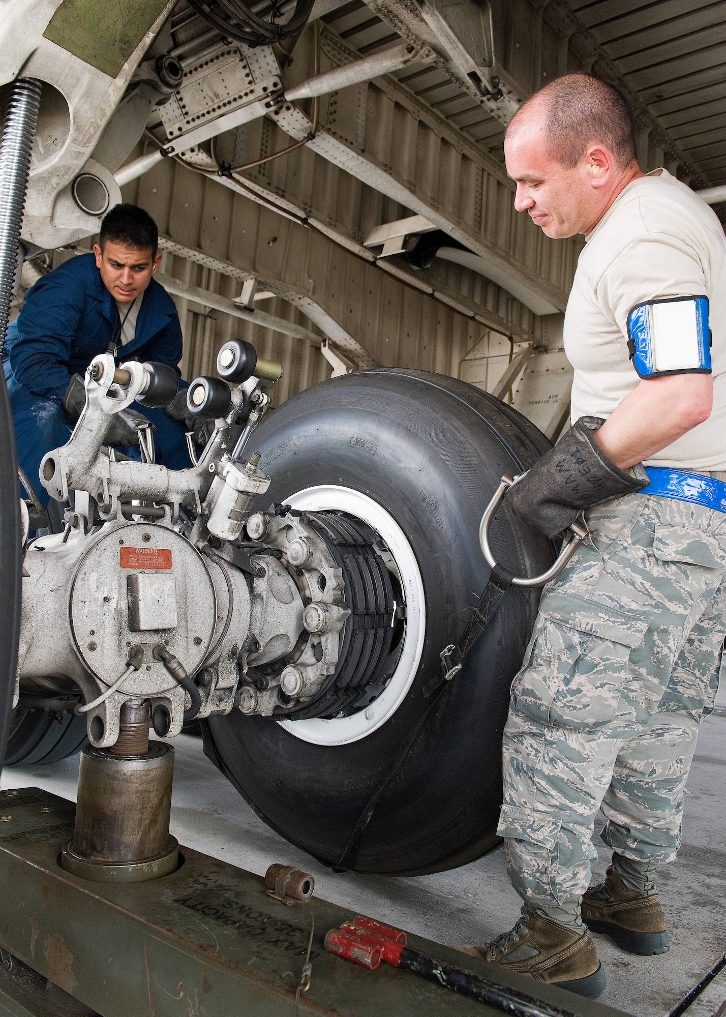 Airman 1st Class Vincent Gaspara, left, and Tech. Sgt. Andrew Hamilton, right, both crew chiefs assigned to the 436th Aircraft Maintenance Squadron, install a new C-5M Super Galaxy main landing gear wheel and tire assembly April 22, 2014, at Dover Air Force Base, Del. The crew chiefs used a harness to lift the 212-pound wheel and tire assembly onto the brake rotor. (U.S. Air Force photo by Roland Balik)