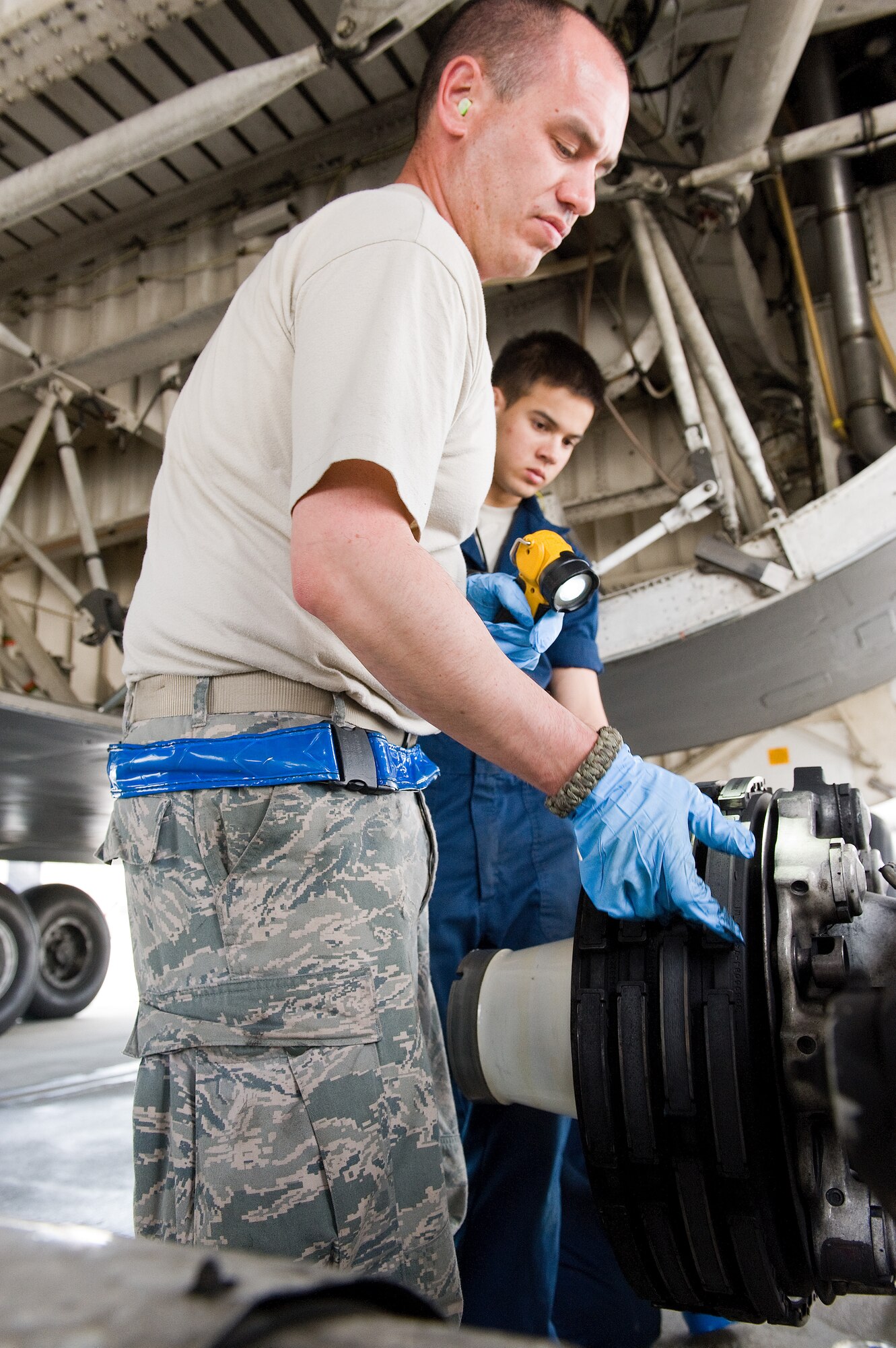 Tech. Sgt. Andrew Hamilton, front, 436th Aircraft Maintenance Squadron crew chief, inspects the main landing gear brake assembly of a C-5M Super Galaxy April 22, 2014, at Dover Air Force Base, Del.. Hamilton inspected the brake rotors in accordance with one of the tire change steps specified in the technical order. Airman 1st Class Nathan Shull, rear, 436th AMXS crew chief, waits to apply new lubricant to the bogie assembly. (U.S. Air Force photo by Roland Balik)