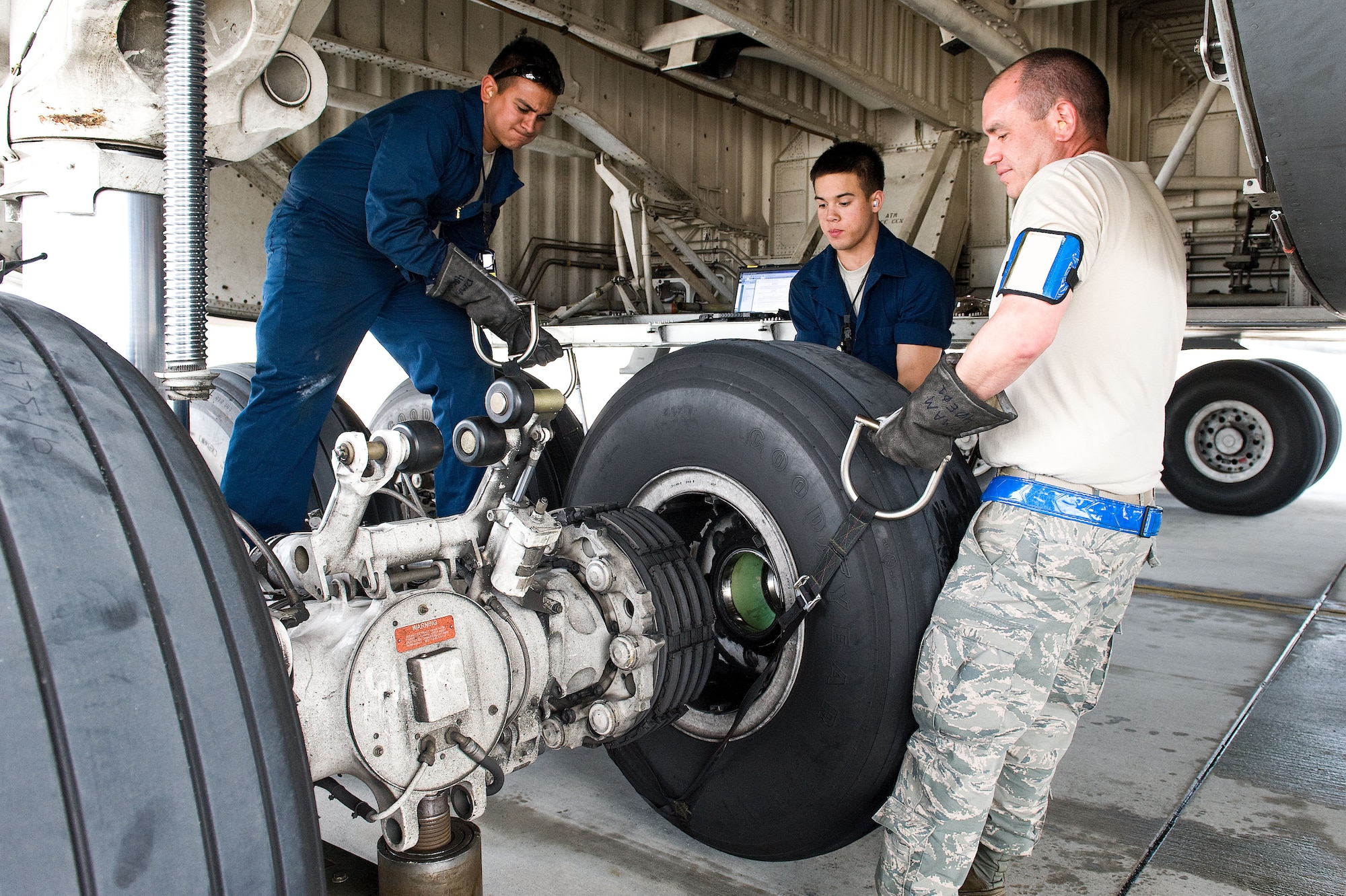 Airman 1st Class Vincent Gaspara, left, and Nathan Shull, center, and Tech. Sgt. Andrew Hamilton, right, all crew chiefs assigned to the 436th Aircraft Maintenance Squadron, remove a C-5M Super Galaxy main landing gear wheel and tire assembly April 22, 2014, at Dover Air Force Base, Del. The crew chiefs removed and replaced the 4A1 tire due to excessive tread wear. (U.S. Air Force photo by Roland Balik)