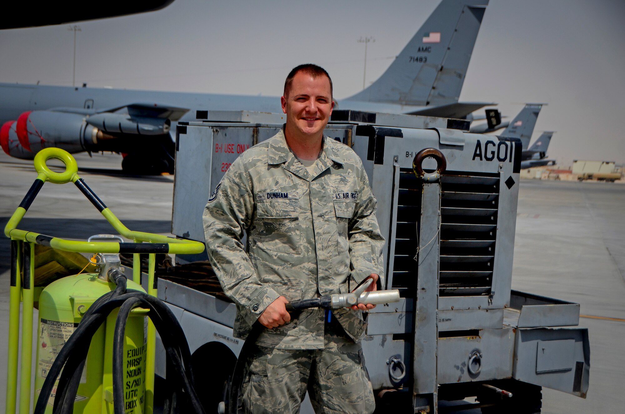 Staff Sgt. William Dunham poses on the flightline in front of a generator, at Al Udeid Air Base, Qatar, April 24, 2014. Dunham, a munitions system specialist assigned to the 379th Expeditionary Aircraft Maintenance Squadron put out a fire on a generator which was hooked up to a B-1B Lancer April 17, 2014. Dunham is a volunteer firefighter for the city of Box Elder, S.D., which is just outside of Ellsworth Air Force Base, S.D., where he is stationed. (U.S. Air Force photo/Senior Airman Jared Trimarchi) 