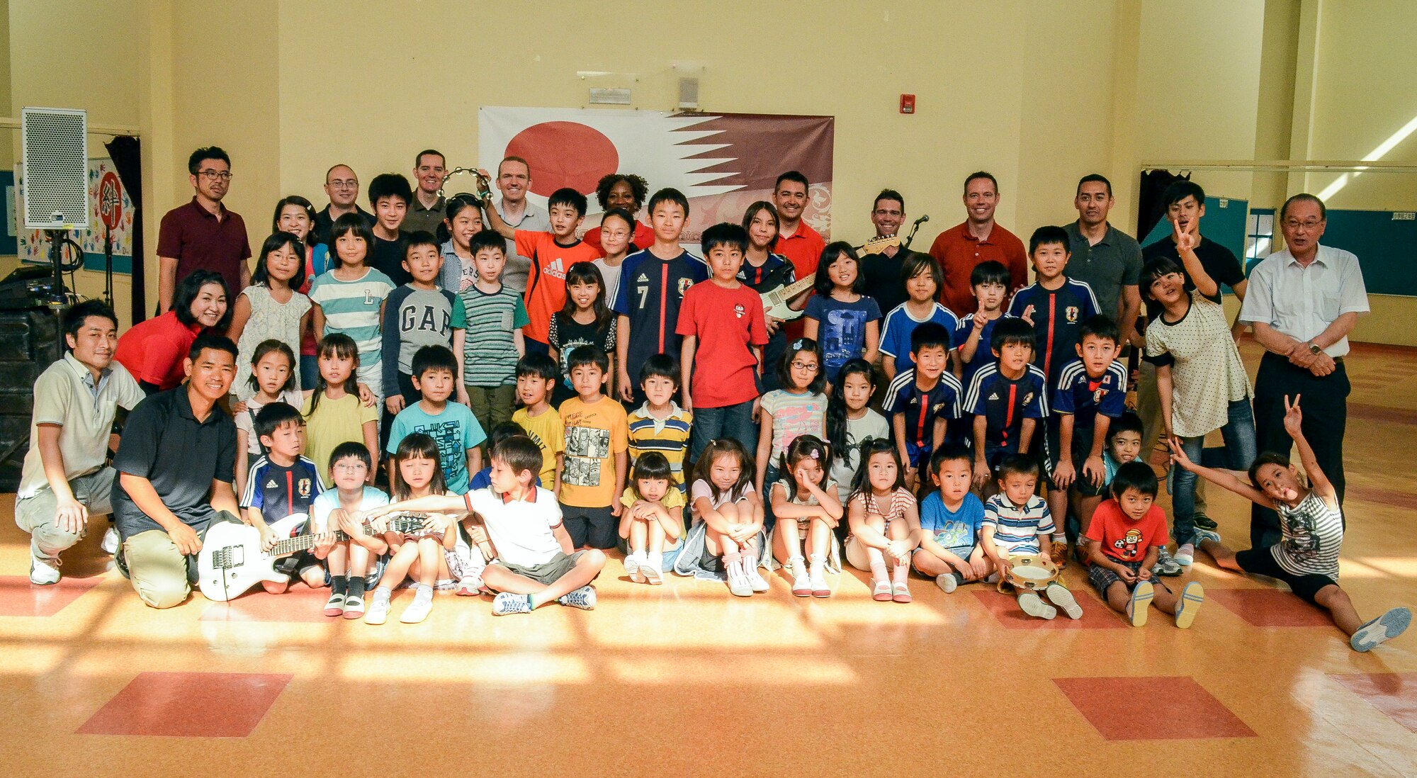 Members of the Air Forces Central Command’s band, “Hypersonic,” pose for a group photo with children and faculty of the Japan School of Doha, Qatar, April 23, 2014. The band’s mission, which is to promote troop morale, diplomacy and outreach to host nation communities, touched home when playing for the Japanese, as the band is deployed from Yokota Air Base, Japan. (U.S. Air Force photo/Senior Airman Jared Trimarchi)