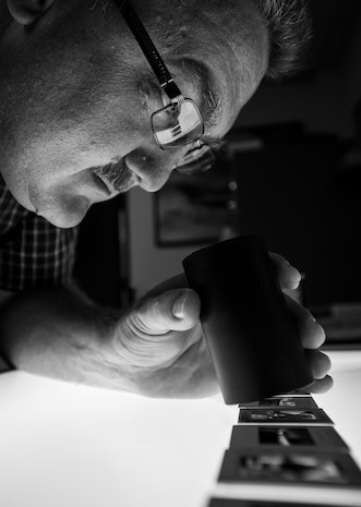 Jason Axberg, 628th Air Base Wing historian, uses a light box and magnifier to review photo slides in search of a specific aircraft April 22, 2014. Most history offices also maintain a repository of photos, videos, photos and other multimedia capturing the history of the base and its assigned units.  (U.S. Air Force photo/ Senior Airman Dennis Sloan)