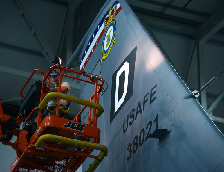 U.S. Air Force Tech. Sgt. Timothy Farmakis, 100th Maintenance Squadron NCO in charge of corrosion control from Las Vegas, shows off the finished “Square D” tail flash on a KC-135 Stratotanker April 24, 2014, in Hangar 814 on RAF Mildenhall, England. The old tail flashes are one giant decal; the newer ones are now a white “D” placed on top of a painted black square. (U.S. Air Force photo by Airman 1st Class Kelsey Waters/Released)
