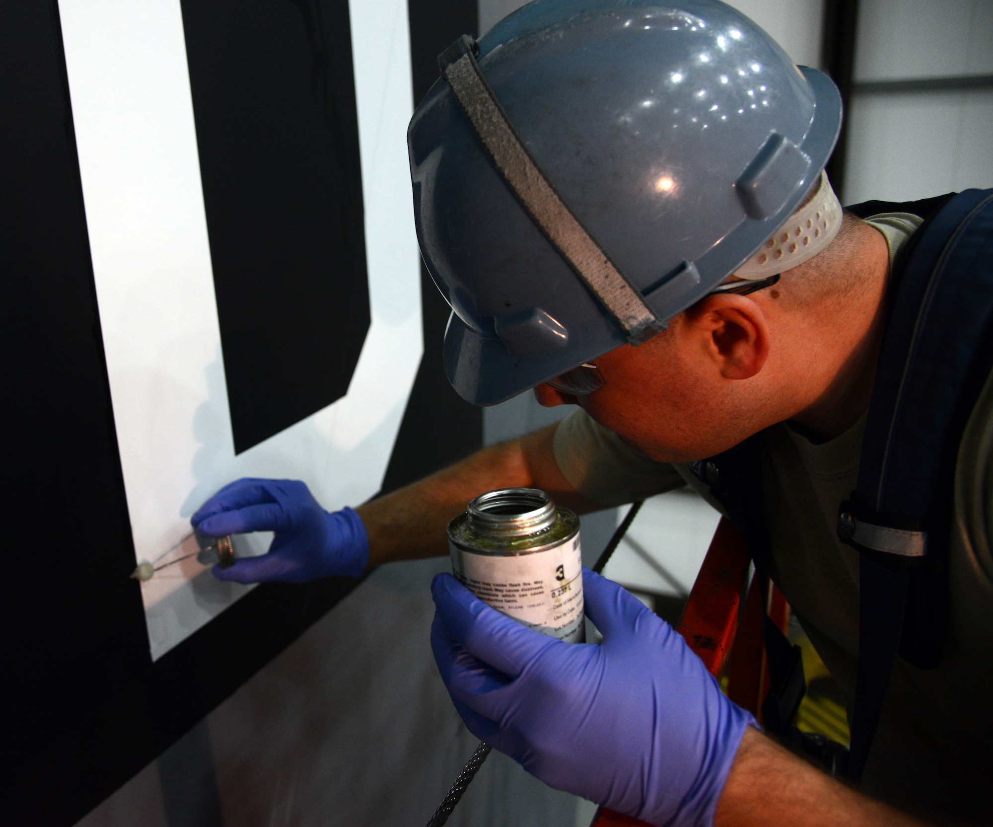U.S. Air Force Tech. Sgt. Timothy Farmakis, 100th Maintenance Squadron NCO in charge of corrosion control from Las Vegas, seals the edges of a “Square D” tail flash on a KC-135 Stratotanker April 24, 2014, in Hangar 814 on RAF Mildenhall, England. The aircraft received a new coat of paint and all-new nose and tail art. (U.S. Air Force photo by Airman 1st Class Kelsey Waters/Released)