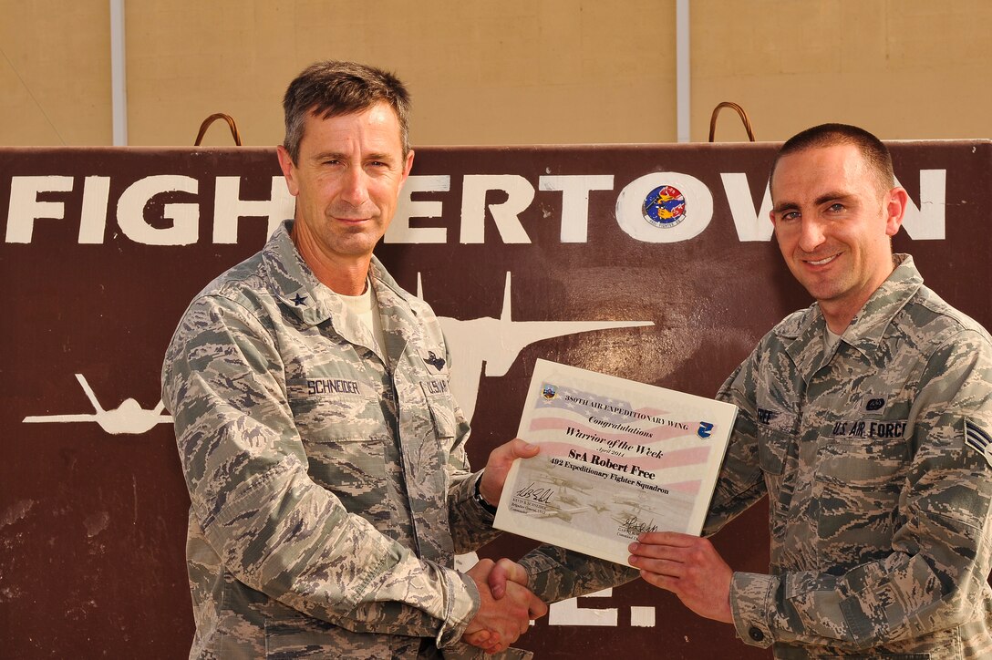 Air Force Brig. Gen. Kevin Schneider, 380th Air Expeditionary Wing commander, presents Senior Airman Robert Free, 492nd Expeditionary Fighter Squadron knowledge operations manager, with a warrior of the week certificate at an undisclosed location in Southwest Asia, April 24, 2014.  Free is a native of Sarasota, Fla. and is deployed from RAF Lakenheath, England. (U.S. Air Force photo by Tech. Sgt. Russ Scalf/Released)