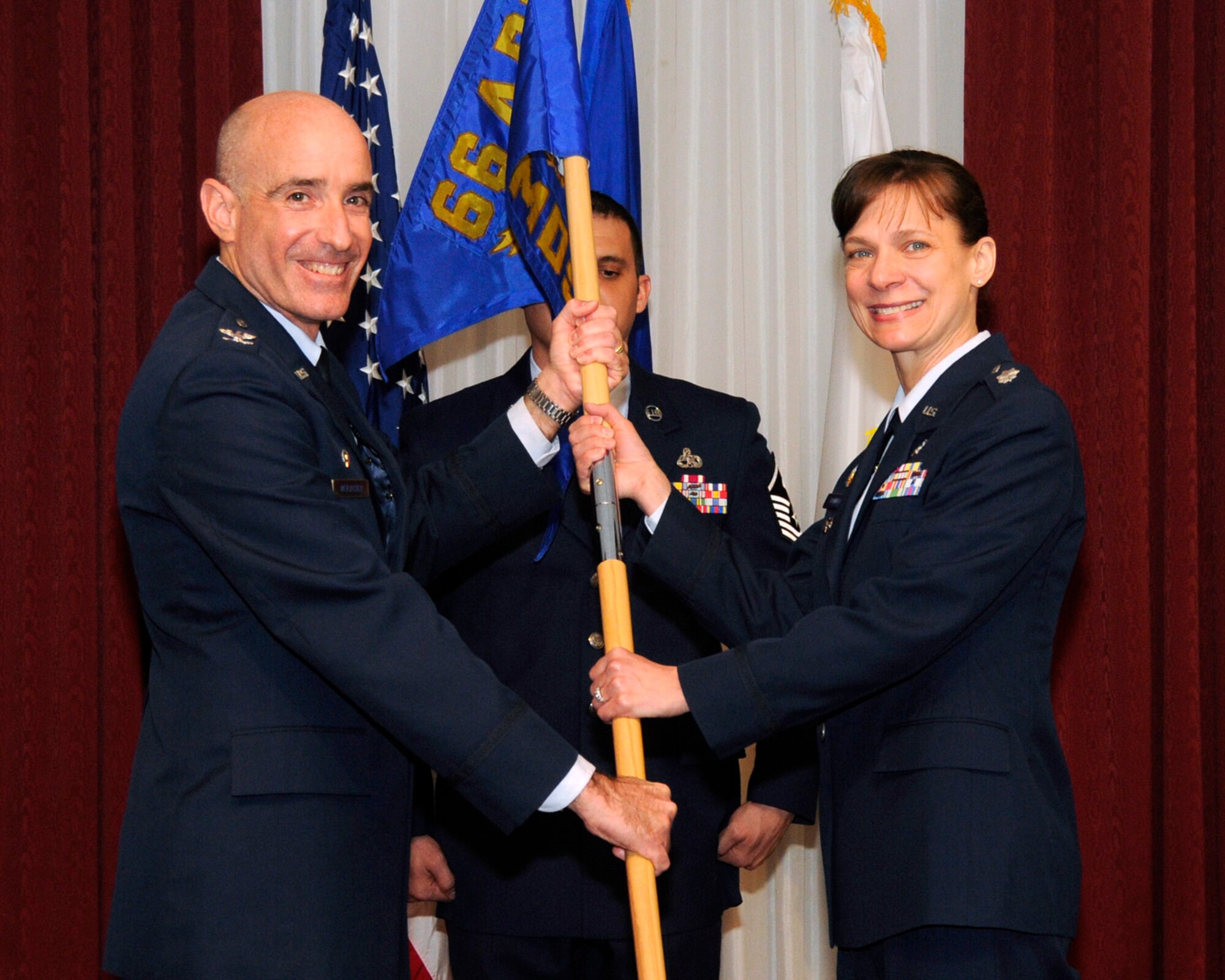 HANSCOM AIR FORCE BASE, Mass. -- Col. Lester A. Weilacher (left), 66th Air Base Group commander, passes the flag to Lt. Col. Therese Bohusch, 66th Medical Squadron commander during the clinic's assumption of command ceremony April 23 in the Minuteman Commons. (U.S. Air Force photo by Linda LaBonte Britt)