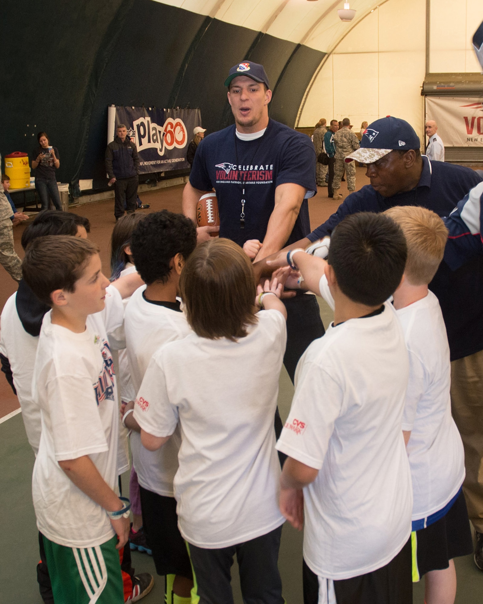 HANSCOM AIR FORCE BASE, Mass. – New England Patriots player Rob Gronkowski (center) and former player Jon Williams (left) lead children through football drills in the Tennis Bubble April 23. As part of the Month of the Military Child celebration and NFL Play 60, past and present players from the New England Patriots as well as Patriots cheerleaders performed a free youth football and cheer clinic. (U.S. Air Force photo by Mark Herlihy)