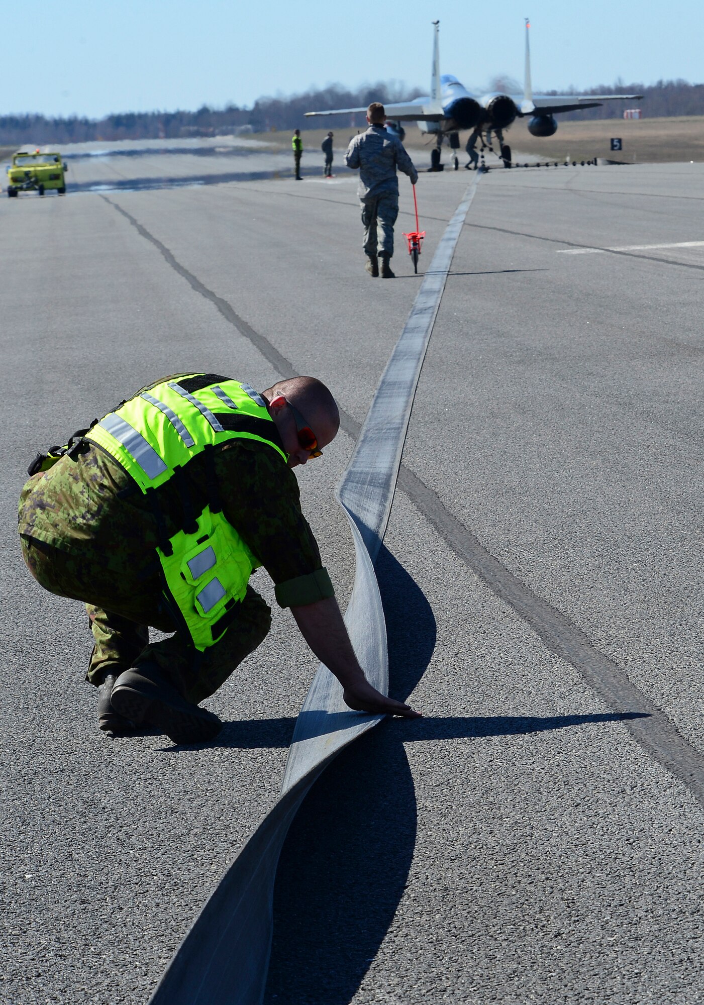 Barrier maintenance Airmen from Estonia and the U.S. measure the pull out length and inspect the purchase tape for damage after a certification barrier engagement at Amari Air Base, Estonia, April 22, 2014. Members of the 48th Air Expeditionary Group recently took a trip to Amari AB to engage and certify the aircraft arresting system, taking a critical step toward validating the new NATO Forward Operating Base. (U.S. Air Force photo by Airman 1st Class Dana J. Butler/Released)