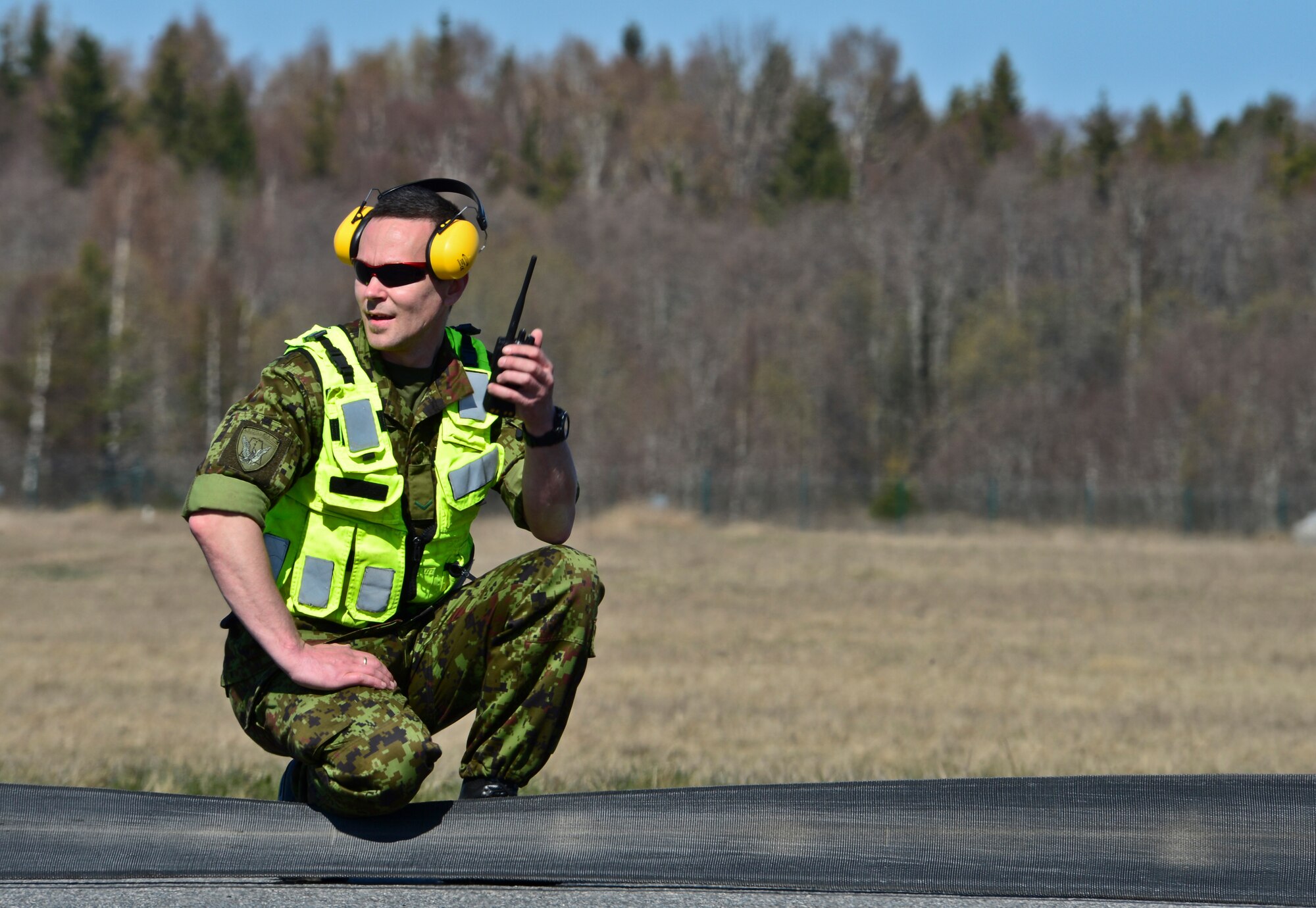 Estonian air force Sergeant 1st Class Hannes Sepp, communicates across the runway after a certification barrier engagement at Amari Air Base, Estonia, April 22, 2014. Members of the 48th Air Expeditionary Group recently took a trip to Amari AB to engage and certify the aircraft arresting system, taking a critical step toward validating the new NATO Forward Operating Base. (U.S. Air Force photo by Airman 1st Class Dana J. Butler/Released)