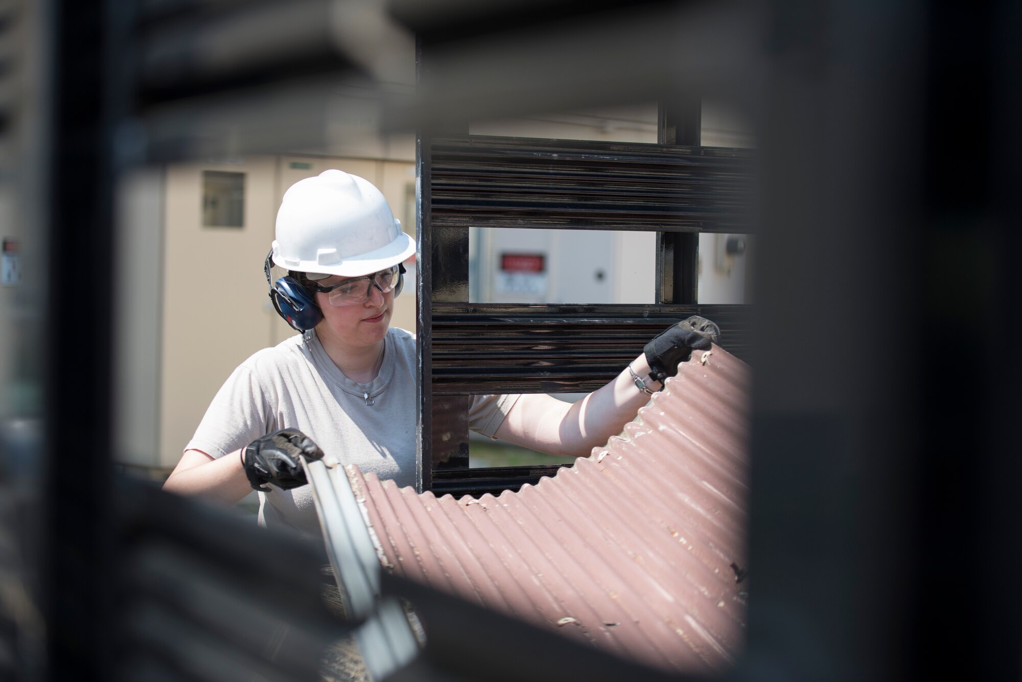 Senior Airman Kristen DiBennedetto, 374th Civil Engineer Squadron structures journeyman, places a sheet of metal from a damaged roof in the back of a truck at Yokota Air Base, Japan, April 24, 2014. DiBennedetto and her team removed the damaged roof covering the dormitory bicycle lot and loaded the metal and scraps into the truck to be disposed of or recycled. (U.S. Air Force photo by Staff Sgt. Cody H. Ramirez/Released)