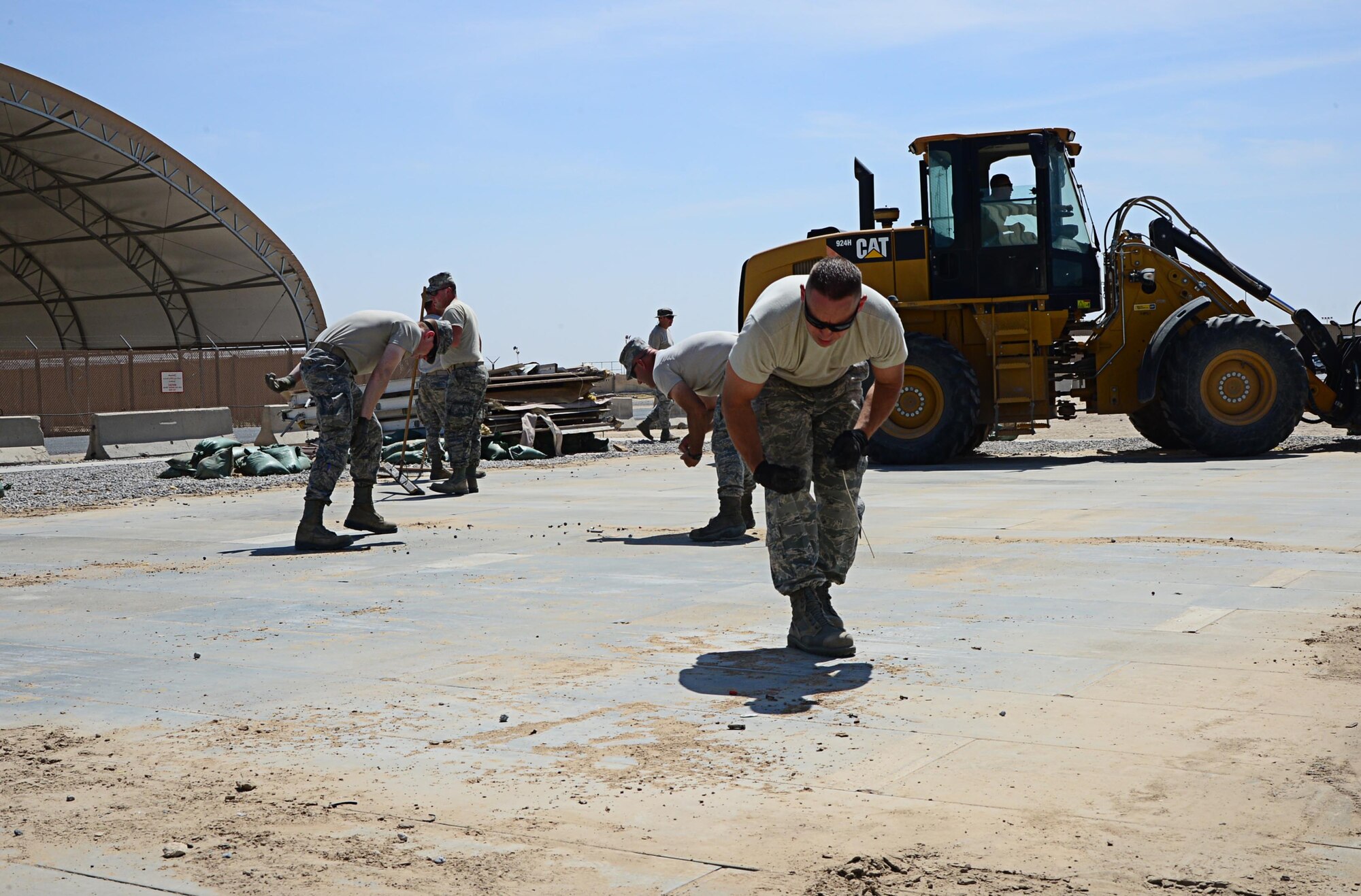 The 386th Expeditionary Civil Engineering Squadron and personnel from the 386th Expeditionary Logistics readiness Squadron remove an old supply tent foundation for ELRS at an undisclosed location in Southwest Asia. A new tent will be constructed in its place to store uniforms for the base. (U.S. Air Force photo by Senior Airman Desiree W. Moye)