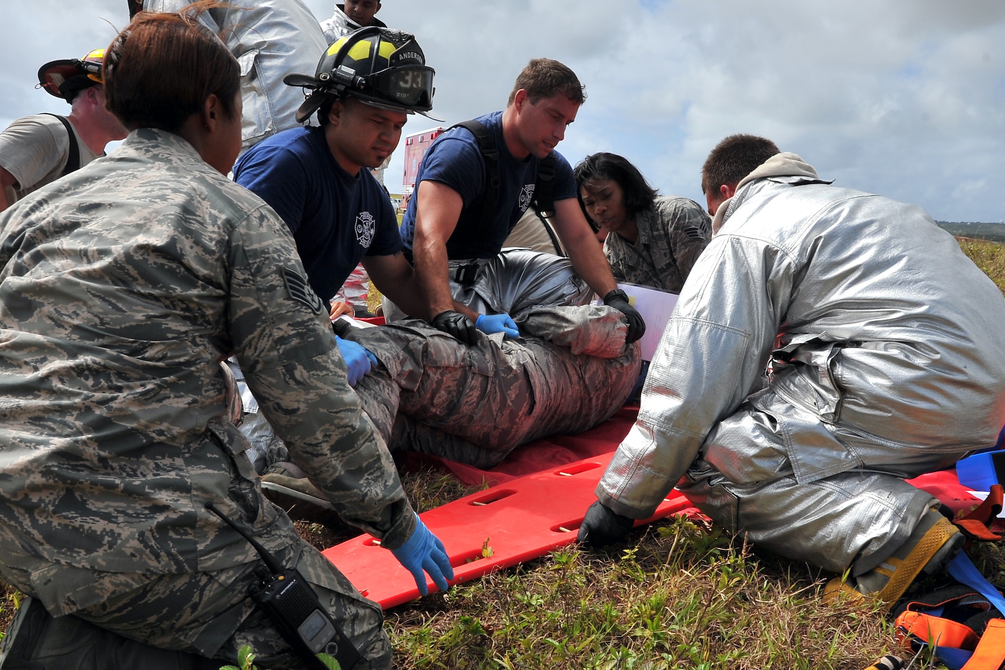 Emergency responders from the 36th Medical Operations Squadron and 36th Civil Engineer Squadron move a simulated patient onto a spine board during an exercise scenario on Andersen Air Force Base, Guam, April 14, 2014. Andersen performs operational readiness exercises regularly to ensure Airmen and their families remain ready to respond quickly and accurately in the event of a real-world situation. (U.S. Air Force photo by Staff Sgt. Melissa B. White/Released)