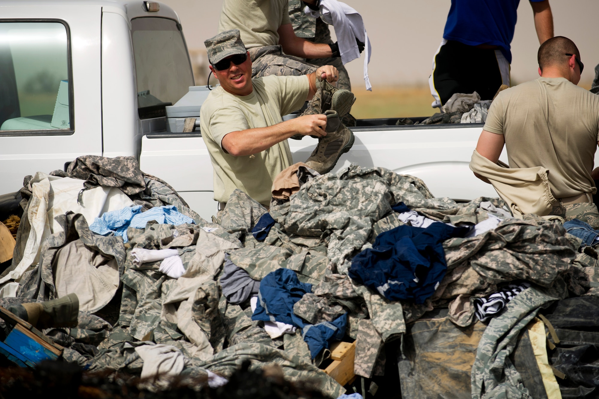 Senior Master Sgt. Donald Simons throws boots on a pile of unservicable uniform items that await destruction during a training burn by the 386th Expeditionary Civil Engineer Squadron Fire Department.  Simmons, the 386th Expeditionary Operations Group's First Sergeant, volunteered to assist with the uniform disposal.  Approximately $105,000 worth of unserviceable uniform items, including boots, were collected over a 12-month period and were destroyed during the blaze on April 18.  (U.S. Air Force photo by Senior Master Sgt. Burke Baker)  