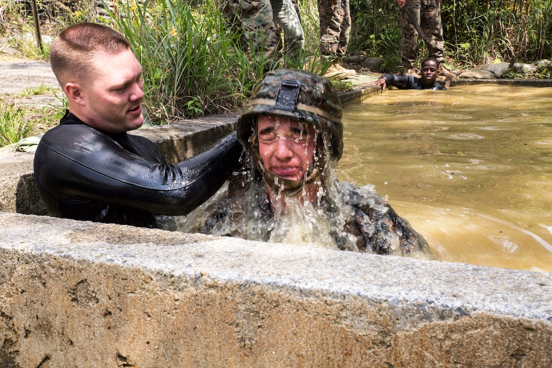 Lance Cpl. Dylan Isabelle, a native of Amherst, N.H., right, resurfaces after swimming through a tunnel during an endurance course April 17 at the Jungle Warfare Training Center on Camp Gonsalves. The endurance course is the culminating event of the weeklong basic jungle survival course. JWTC is the only facility of its type in the Department of Defense. Isabelle is a combat engineer with Combat Assault Battalion, 3rd Marine Division, III Marine Expeditionary Force. (U.S. Marine Corps photo by Cpl. Stephen D. Himes/Released)

