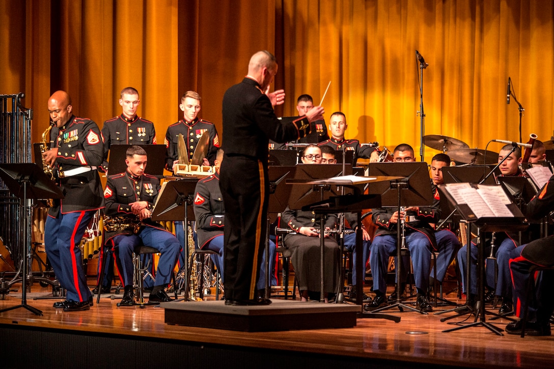 Chief Warrant Officer Joshua A. Stone, center, conducts the III Marine Expeditionary Force Band as Staff Sgt. DeMarius Jackson, far left, performs a solo on the saxophone March 14 during a combined concert at the Camp Foster Theater. The concert paired the III MEF Band with the University of the Ryukyus Wind Orchestra Band Club. This event marked the second such concert the two bands performed together. Stone is the director of the III MEF Band, and Jackson is a musician with the band. 