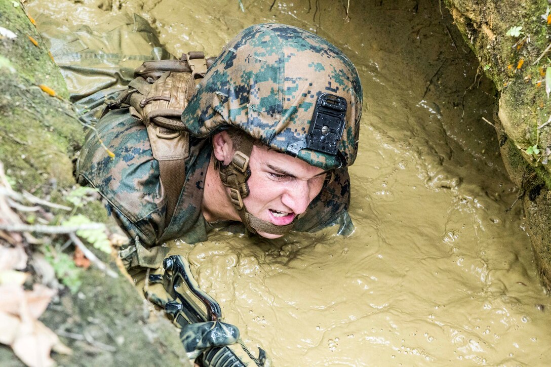 Lance Cpl. George Redhead, a native of San Jose, Calif., low crawls through the muddy water of the “pit-and-pond” section of the endurance course April 17 at the Jungle Warfare Training Center on Camp Gonsalves. The jungle is vastly different from the desert terrain many Marines have been training in for the past decade, according to Kao. The jungle does not allow for significant mechanized or motorized movements, which forces Marines to hone their dismounted warfighting abilities. Redhead is a rifleman with 3rd Light Armored Reconnaissance Battalion currently assigned to Combat Assault Battalion, 3rd Marine Division, III Marine Expeditionary Force, under the unit deployment program. Kao is a native of Vancouver, Wash., and is the camp commander for Camp Gonsalves, Marine Corps Base Camp Smedley D. Butler, Marine Corps Installations Pacific. (U.S. Marine Corps photo by Cpl. Stephen D. Himes/Released)