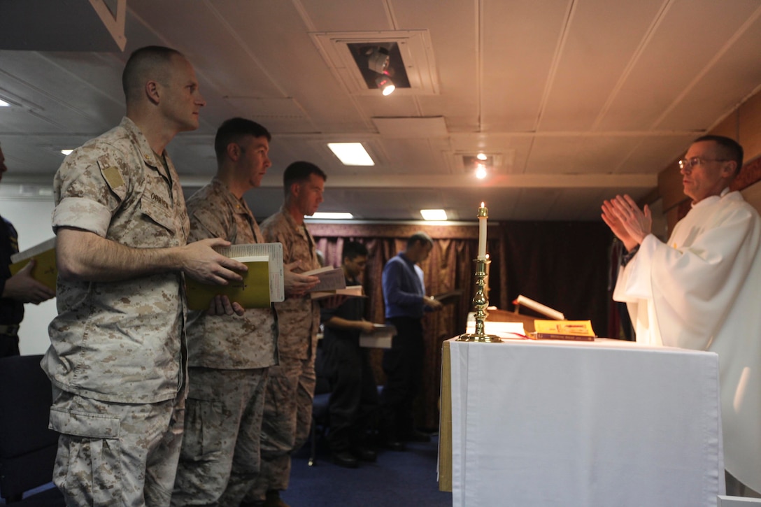 Commander William J. Muhm (right), command chaplain for the USS Bonhomme Richard (LHD 6), and a native of New York City, leads a Catholic mass service for Marines and sailors during Holy Week on the BHR here, April 17. Holy Week is a week-long celebration leading up to Easter Sunday. The 31st MEU recently returned from participation in Exercise Ssang Yong ‘14 in the Republic of Korea and conducting theater security cooperation operations in the Asia-Pacific region. 