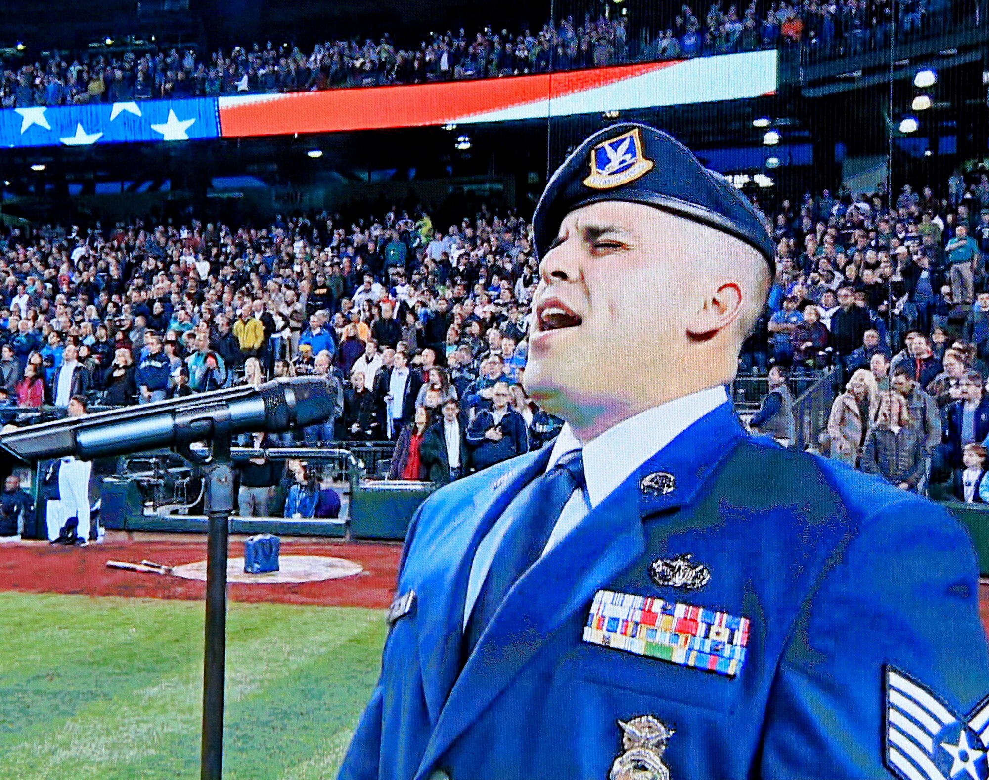 Tech. Sgt. Freddie Garza, 446th Security Forces Squadron, sings "God Bless America" during the seventh inning of a Seattle Mariners vs. Texas Ranger baseball game. Garza was chosen to sing in honor of the 2014 Seattle Mariners Salute to Armed Forces Night on April 26, which was a night dedicated to supporting all active and prior members of the military. (U.S. Air Force Reserve Photo by Senior Airman Madelyn McCullough)
