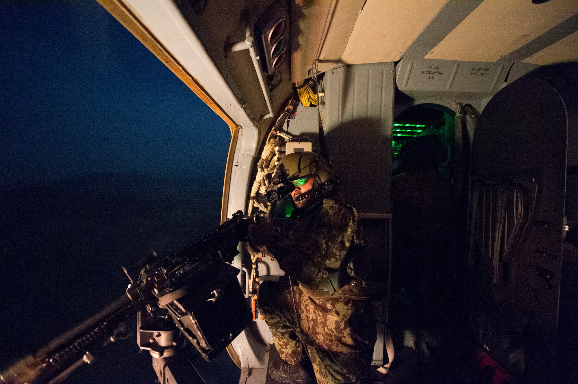 An Afghan air force Mi-17 aerial gunner fires an M-240 machine gun while flying over a weapons range March 13, 2014, near Kabul, Afghanistan. U.S. Air Force airmen from the 438th Air Expeditionary Wing/NATO Air Training Command-Afghanistan flew a night vision goggle training mission with an AAF aircrew to further increase the operational capability of the AAF. (U.S. Air Force photo/Tech. Sgt. Jason Robertson)         