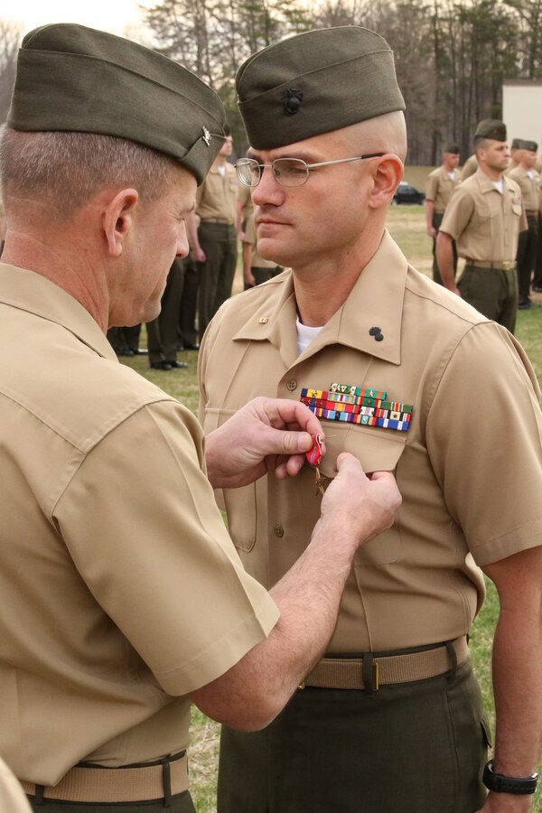 Col. Colonel Todd S Desgrosseilliers, commanding officer of The Basic School, pins the Bronze Star Medal with combat distinguishing device onto Warrant Officer Jeremy Barone at The Basic School aboard Marine Corps Base Quantico on April 11, 2014. Barone received the award for heroic service while serving as the first sergeant with Co. F, 2nd Bn., 8th Marines, 2nd Marine Expeditionary Force Headquarters Group Forward, from April- October 2013, while deployed to Afghanistan during Operation Enduring Freedom.