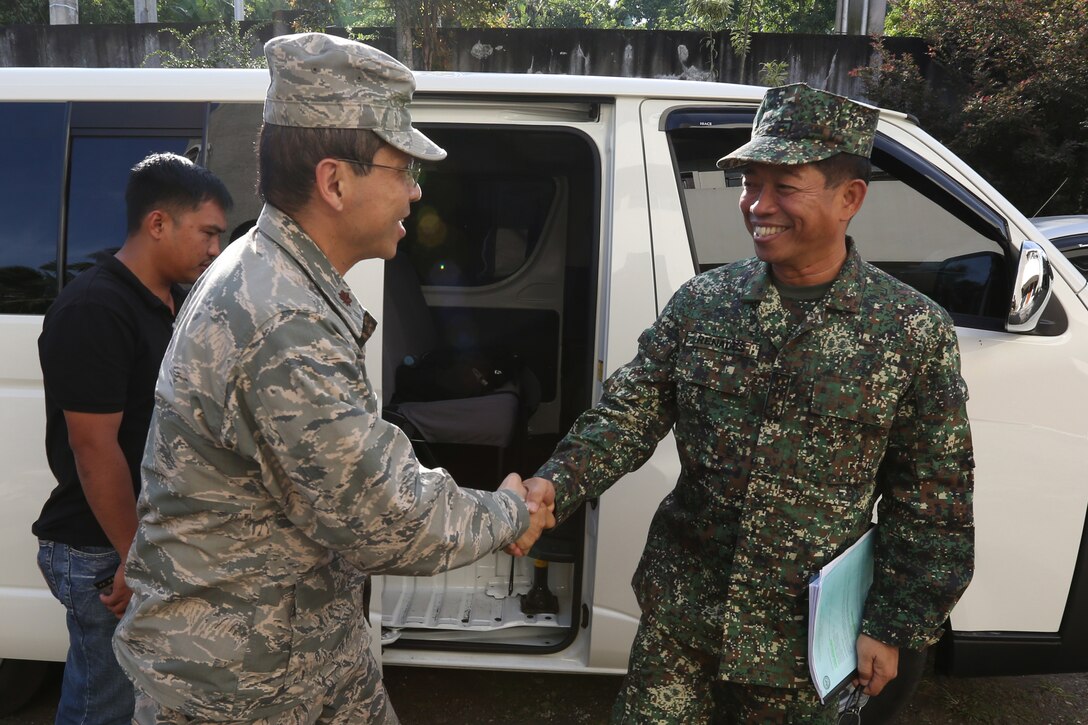 Philippine Navy Capt. Ramon Renales, right, the commander of the Joint Civil-Military Operations Task Force, shakes hands with U.S. Air Force Maj. Herb Shao, assigned to Pacific Air Forces, before a meeting with Bishop Joel Baylon, with the Diocese of Legazpi, during exercise Balikatan 2014 in Legazpi, Philippines, April 21, 2014. Balikatan is an annual bilateral training exercise designed to increase interoperability between the Armed Forces of the Philippines and the U.S. military when responding to future natural disasters. (U.S. Marine Corps photo by Lance Cpl. Trever Statz/Released)