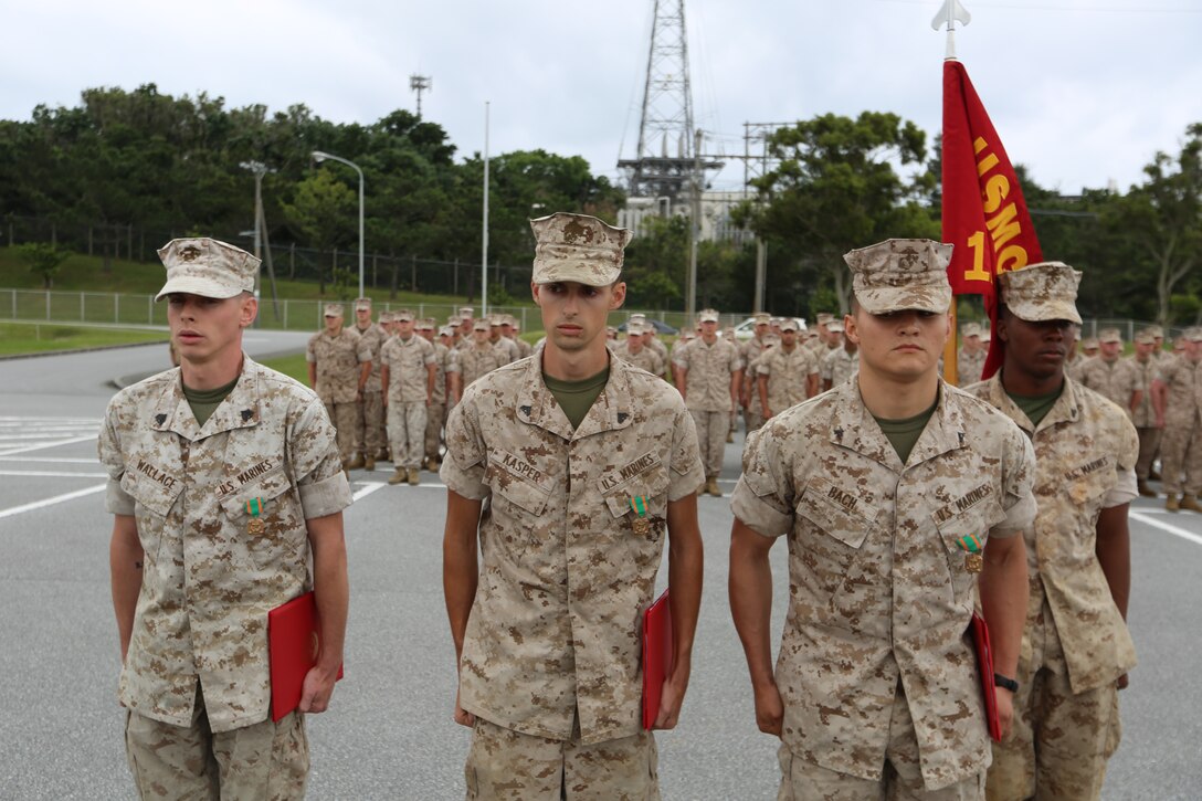 Sgt. Blake A. Wallace, left, Cpl. James A. Kasper, center, and Lance Cpl. Steward M. Bach stand at attention after being awarded the Navy and Marine Corps Achievement Medal April 25 at Camp Hansen. The Marines were recognized for meritorious actions that saved the life of a fellow Marine, who suffered a heart attack. During the ordeal, the Marines performed CPR and additional emergency techniques they learned throughout their Marine Corps training. Wallace and Bach are fire support men, and Kasper is a field artillery fire control man. All three are with Headquarters Battalion, 12th Marine Regiment, 3rd Marine Division, III Marine Expeditionary Force. (U.S. Marine Corps photo by Lance Cpl. Matt Myers/Released)      