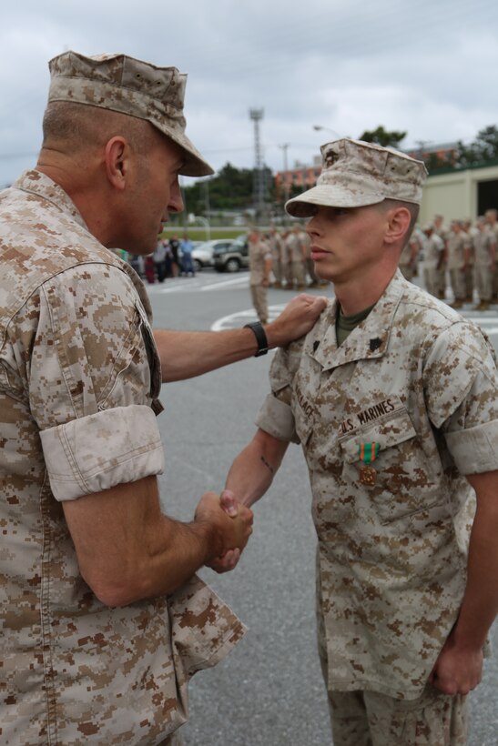 Sgt. Blake A. Wallace, right, is awarded the Navy and Marine Corps Achievement Medal by Col. Lance A. McDaniel April 25 at Camp Hansen. Wallace and two other Marines used emergency medical techniques to save the life of a fellow Marine, who suffered a heart attack. “Everyone knows that in this organization, no Marine is left behind,” said McDaniel. “This matters everywhere we go, not just on the battlefield, but in garrison as well. These Marines honored that principle when they provided assistance.” Wallace is a fire support man with Headquarters Battalion, 12th Marine Regiment, 3rd Marine Division, III Marine Expeditionary Force. McDaniel is the commanding officer of the battalion. (U.S. Marine Corps photo by Lance Cpl. Matt Myers/Released)      