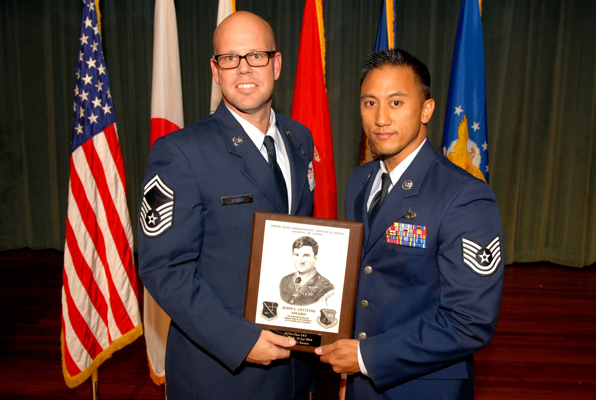 U.S. Air Force Tech. Sgt. Alan Santos, 718th Aircraft Maintenance Squadron, receives the John L. Levitow award from Senior Master Sgt. Aaron Kigar, 18th Operations Support Squadron superintendent, during the NCO Academy class 14-3 graduation ceremony at the Keystone Theater on Kadena Air Base, Japan, April 25, 2014. This distinguished award, named in memory of Medal of Honor recipient Airman 1st Class John L. Levitow, is presented to the most outstanding member of professional military education and denotes superior achievement as both a leader and a scholar. (U.S. Air Force photo by Airman 1st Class Stephen G. Eigel)