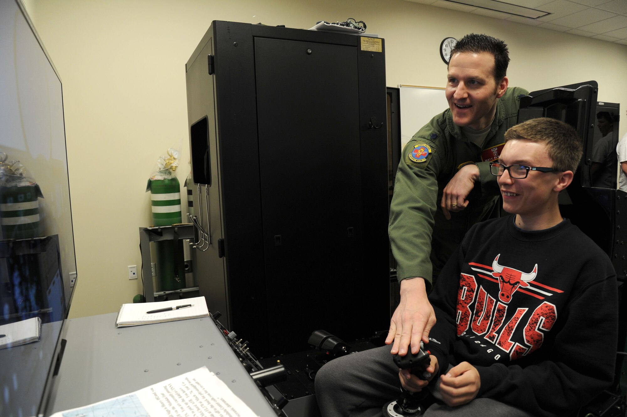 Lt. Col. Matthew Albright instructs a student from Bancroft High School on an aircraft piloting simulator during a base tour at Fairchild Air Force Base, Wash., April 25, 2014. Students received a tour that held stops at the Survival School Exhibits Lab, Aerospace Physiology and a KC-135 Stratotanker static display. Albirght is the aerospace physiological training flight commander of the 92nd Aerospace Medicine Squadron. (U.S. Air Force photo by Airman 1st Class Janelle Patiño/ Released)