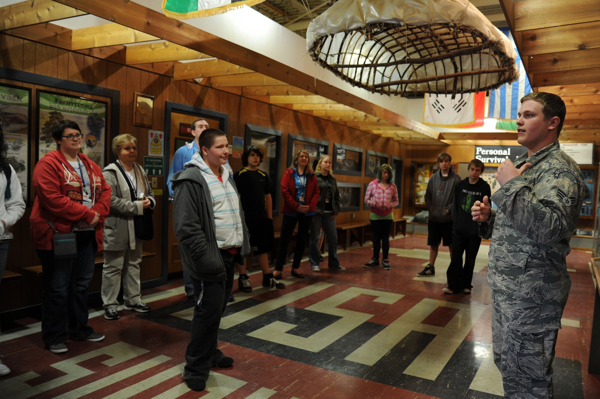 Senior Airman Brody Jett briefs students from Bancroft High School during a base tour at Fairchild Air Force Base, Wash., April 25, 2014. Students received a tour that held stops at the Survival School Exhibits Lab, Aerospace Physiology and a KC-135 Stratotanker static display. Jett is an instructor from the 22nd Training Squadron. (U.S. Air Force photo by Airman 1st Class Janelle Patiño/ Released)