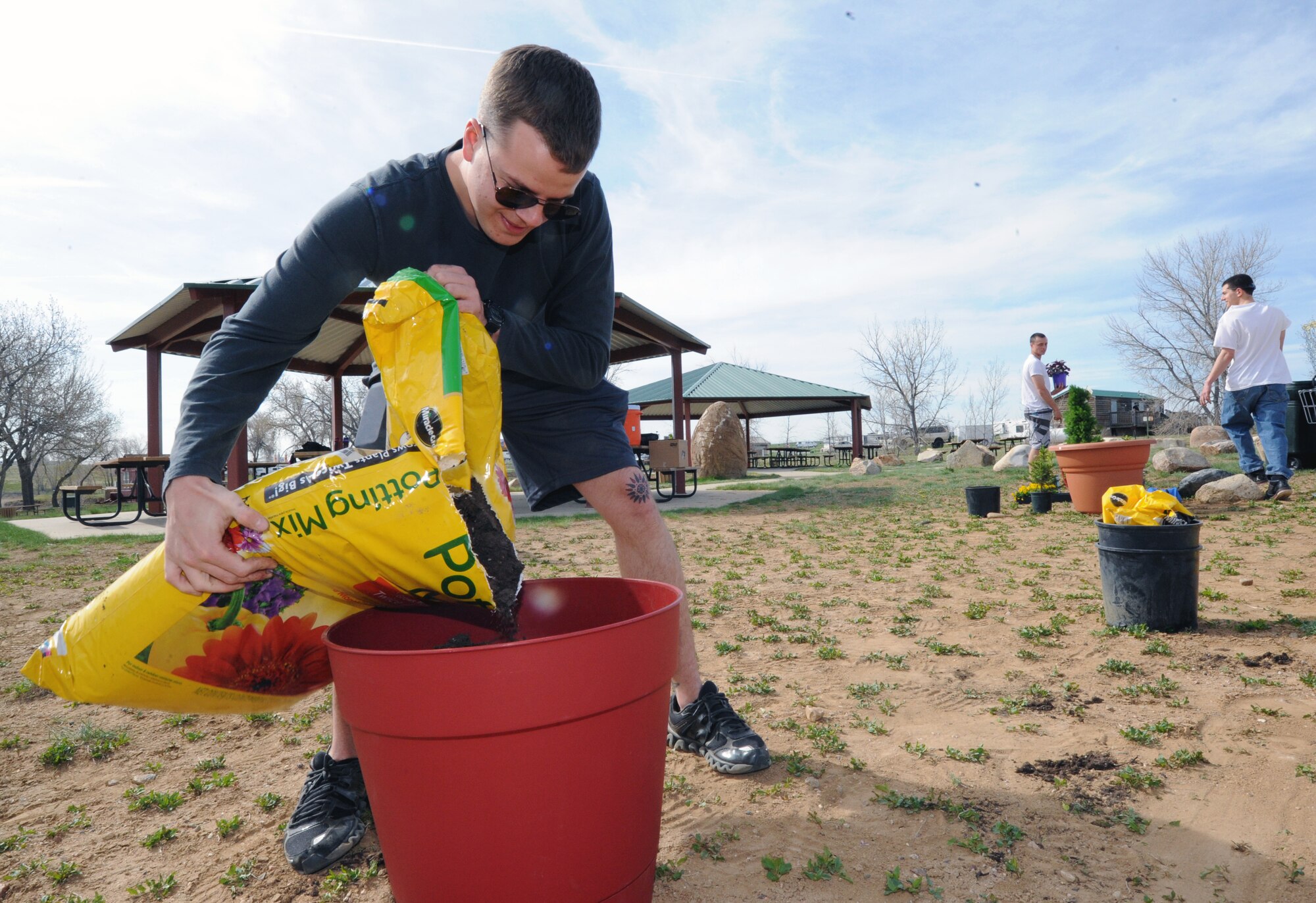 Airman 1st Class Matthew Bruce, 460th Space Communications Squadron touch maintenance, pours soil into a planting pot to celebrate Earth Day April 22, 2014, at the outdoor recreation pavilions on Buckley Air Force Base, Colo. The celebration included lunch, nature projects and games to recognize the value of a clean and safe environment. (U.S. Air Force photo by Airman Emily E. Amyotte/Released)